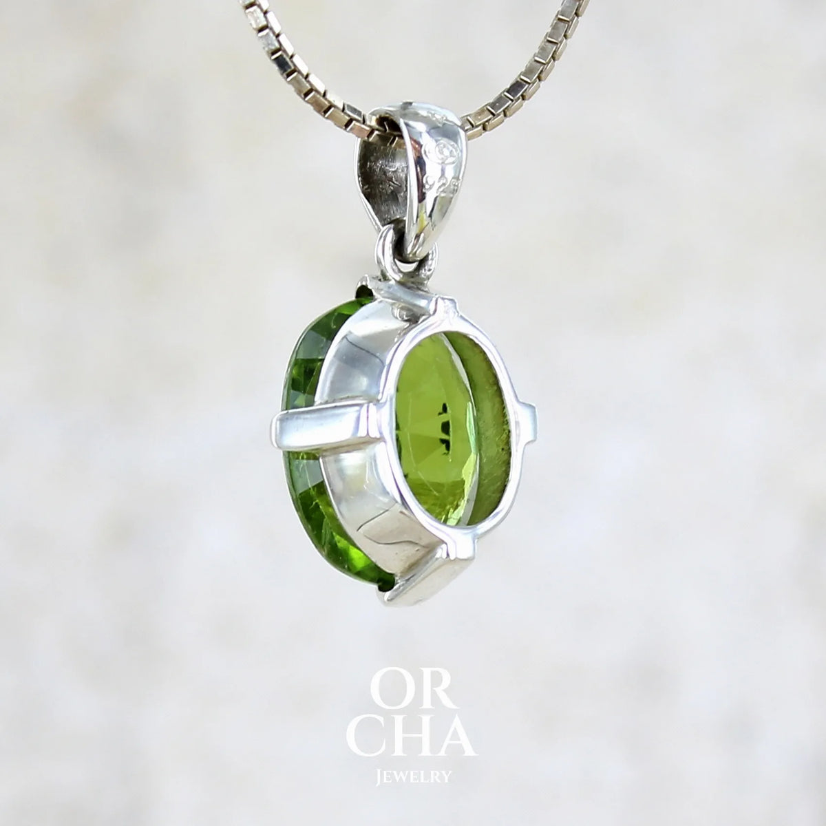 Vue de dos d'un pendentif pour femme en argent massif serti d'un Péridot de couleur vert olive doré profond et intense . Pierre taillée transparente présentant des inclusions, de forme ovale. Bijoux unique par Orchajewelry