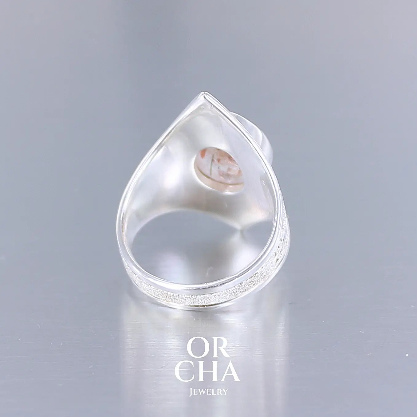 vue arrière d'une bague pour femme en argent massif sculptées d'étoiles et autres corps célestes sertie d'une pierre de soleil aux nuances orangées rouges scintillantes. Pierre naturelle, facettée de forme ovale, de qualité transparente pierre transparente avec inclusions scintillantes d'hématites. Taille 59. Bijoux unique, éthique et durable présenté dans un coffret de notre marque, prêt à offrir. Livraison offerte, certificat d'authenticité, service client.
