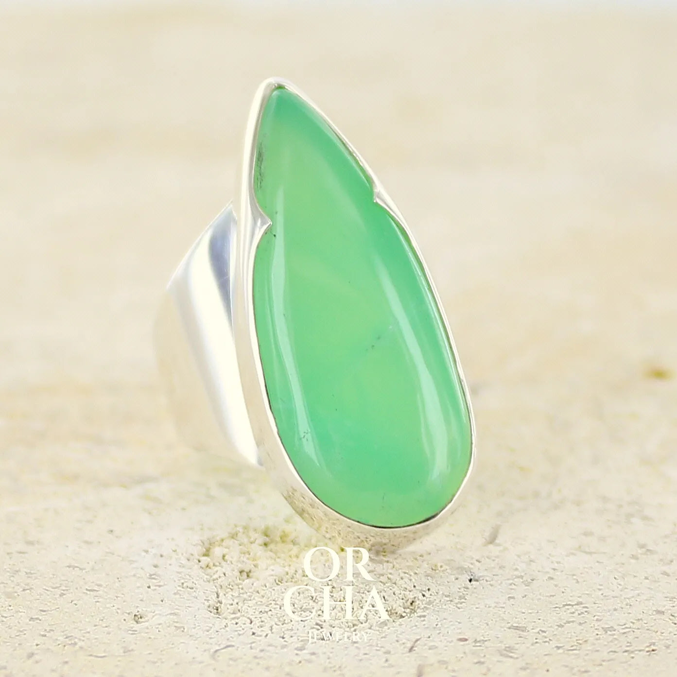 Grande Bague pour femme en argent massif, sertie d'un cabochon de chrysoprase. Pierre naturelle de couleur verte taillée en forme de goutte de qualité translucide. Bijoux unique réalisé en taille 54 par Orchajewelry