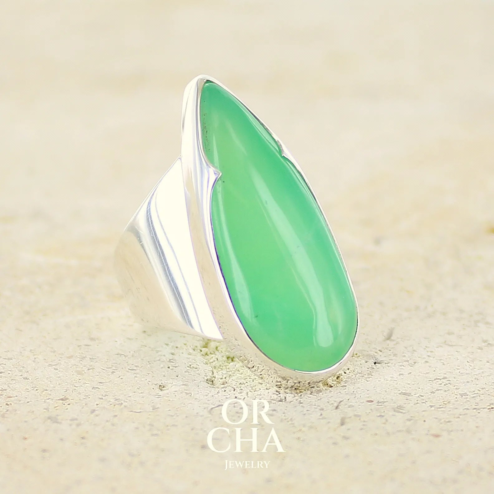 Grande Bague pour femme en argent massif, sertie d'un cabochon de chrysoprase. Pierre naturelle de couleur verte taillée en forme de goutte de qualité translucide. Bijoux unique réalisé en taille 54 par Orchajewelry