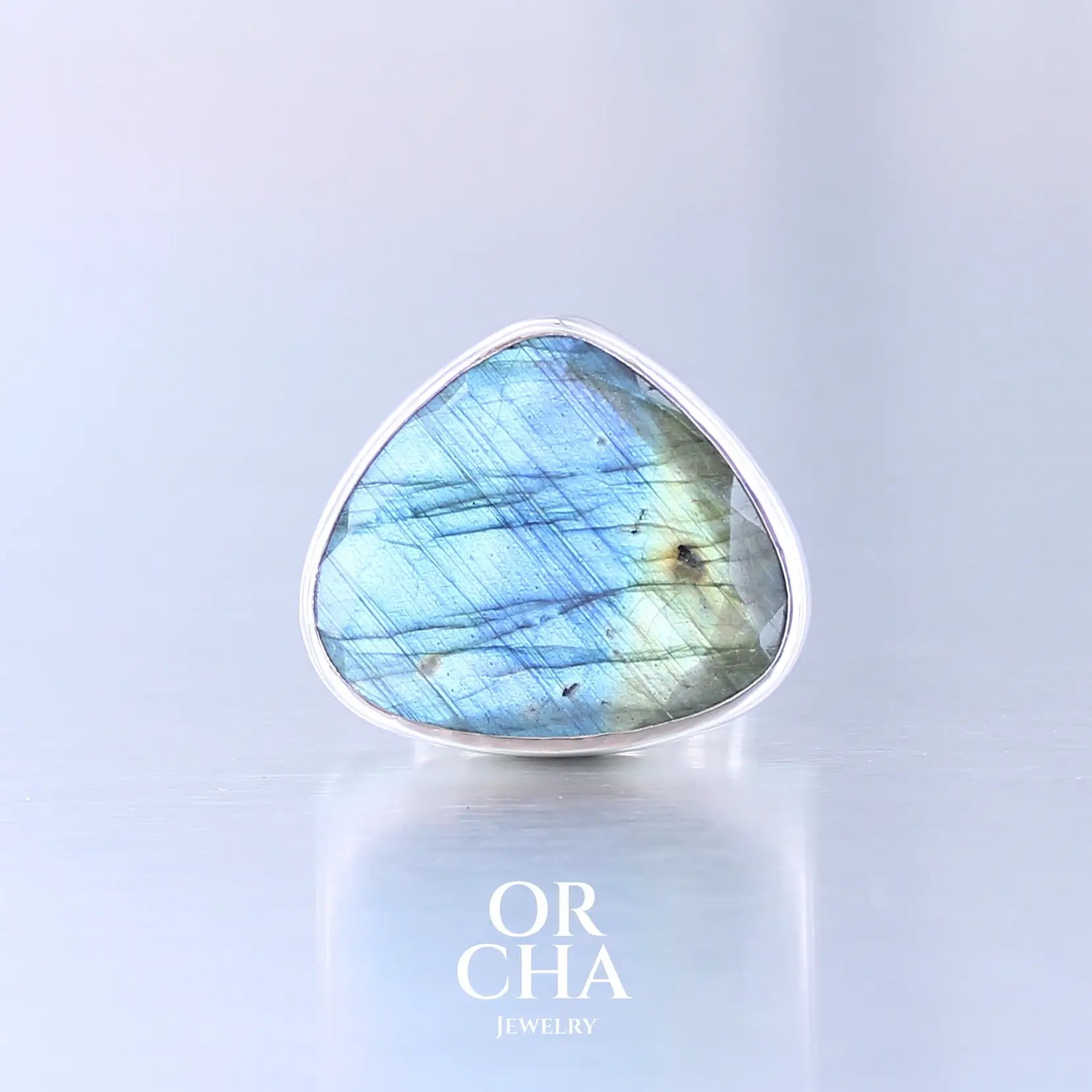 Bague pour femme en argent massif sertie d'une labradorite aux reflets bleus et verts selon la lumière. Pierre facettée naturelle translucide présentant des inclusions fréquents sur ce type de pierre. Taille 56. Bijoux unique, éthique et durable présenté dans un coffret de notre marque, prêt à offrir. Livraison offerte, certificat d'authenticité, service client.

