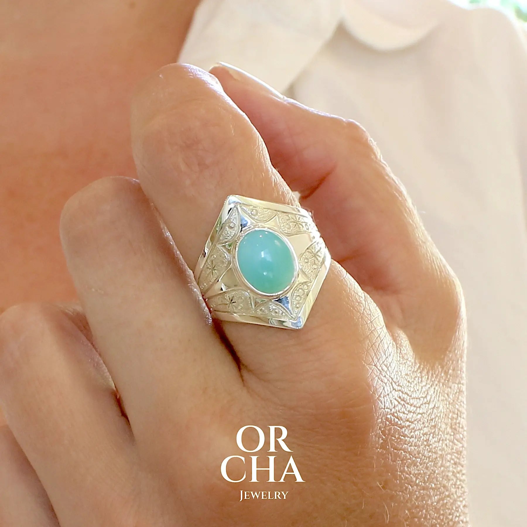 Photo portée d'une bague pour femme en argent massif, sertie d'un cabochon d'opale bleue du Pérou de couleur bleu ciel turquoise. Pierre taillée de forme ovale de qualité opaque. Bijou unique réalisé en taille 60,5.