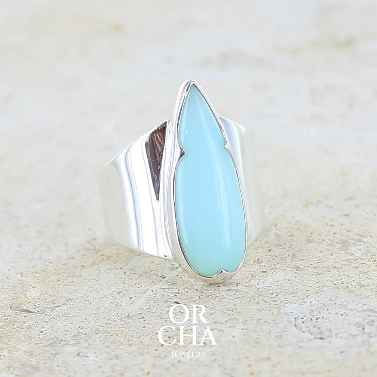 Bague pour femme en argent massif, sertie d'un cabochon d'opale bleue du Pérou de couleur bleu ciel. Pierre taillée en forme de goutte longiligne, de qualité opaque. Bijou unique réalisé en taille 53,5. 