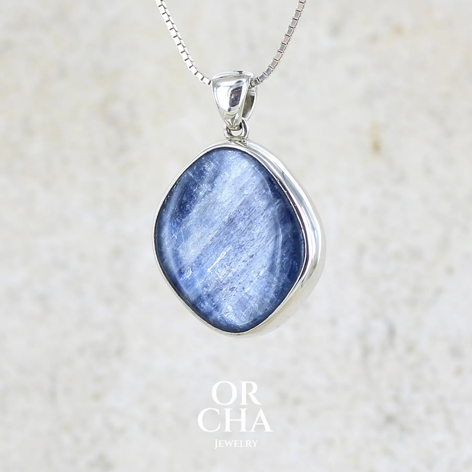 Pendentif en argent massif serti d'un cabochon de cyanite de couleur bleue jeans nacré. Pierre de qualité opaque comportant des inclusions. Bijoux unique par Orcha Jewelry