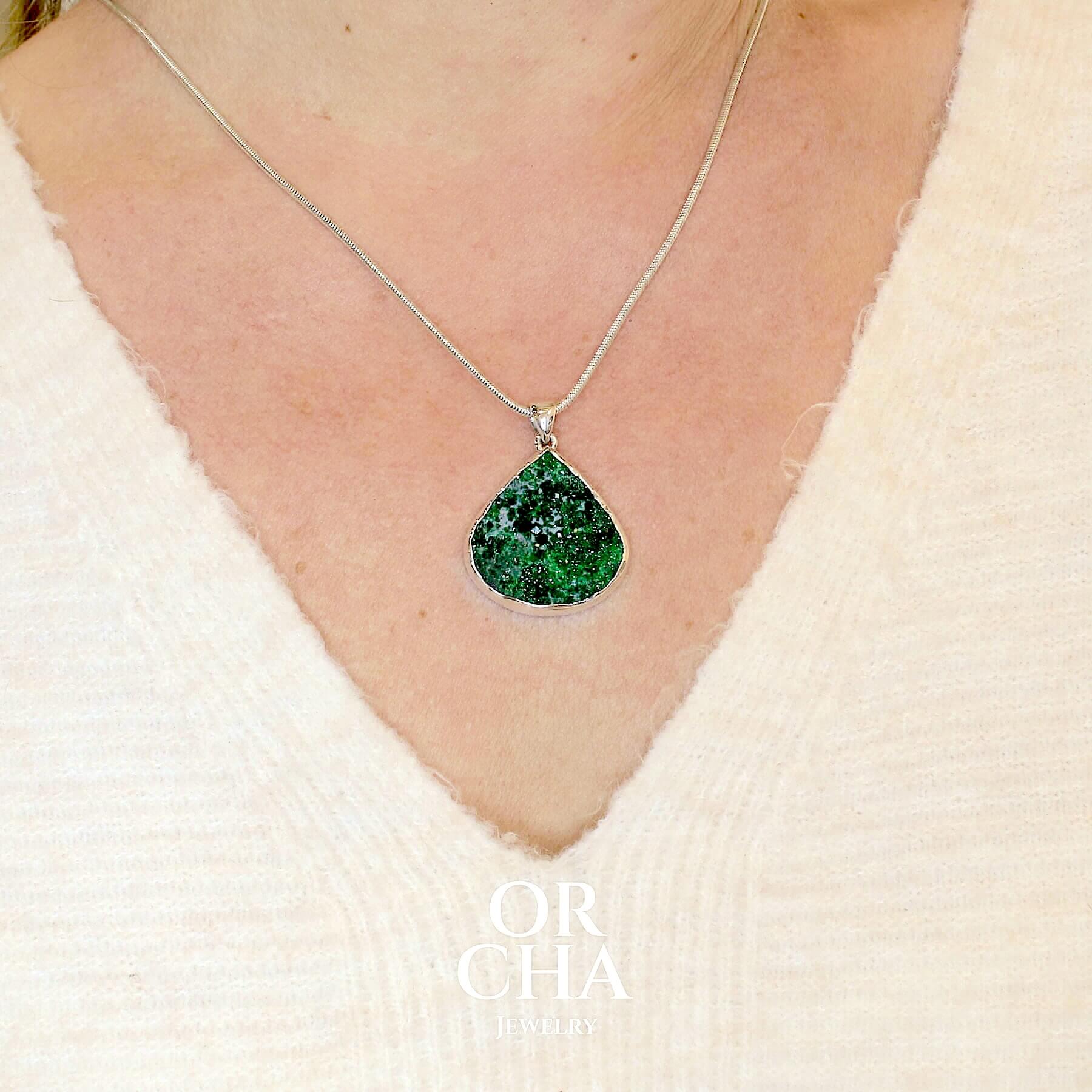 Pendentif en argent massif serti d'une Uvarovite brute ( variété de Grenat ). Pierre brute recouverte de cristaux scintillants de couleur verte, taillée en forme de goutte. Bijoux unique, éthique et durable présenté dans un coffret de notre marque, prêt à offrir. Livraison offerte, certificat d'authenticité, service client.
