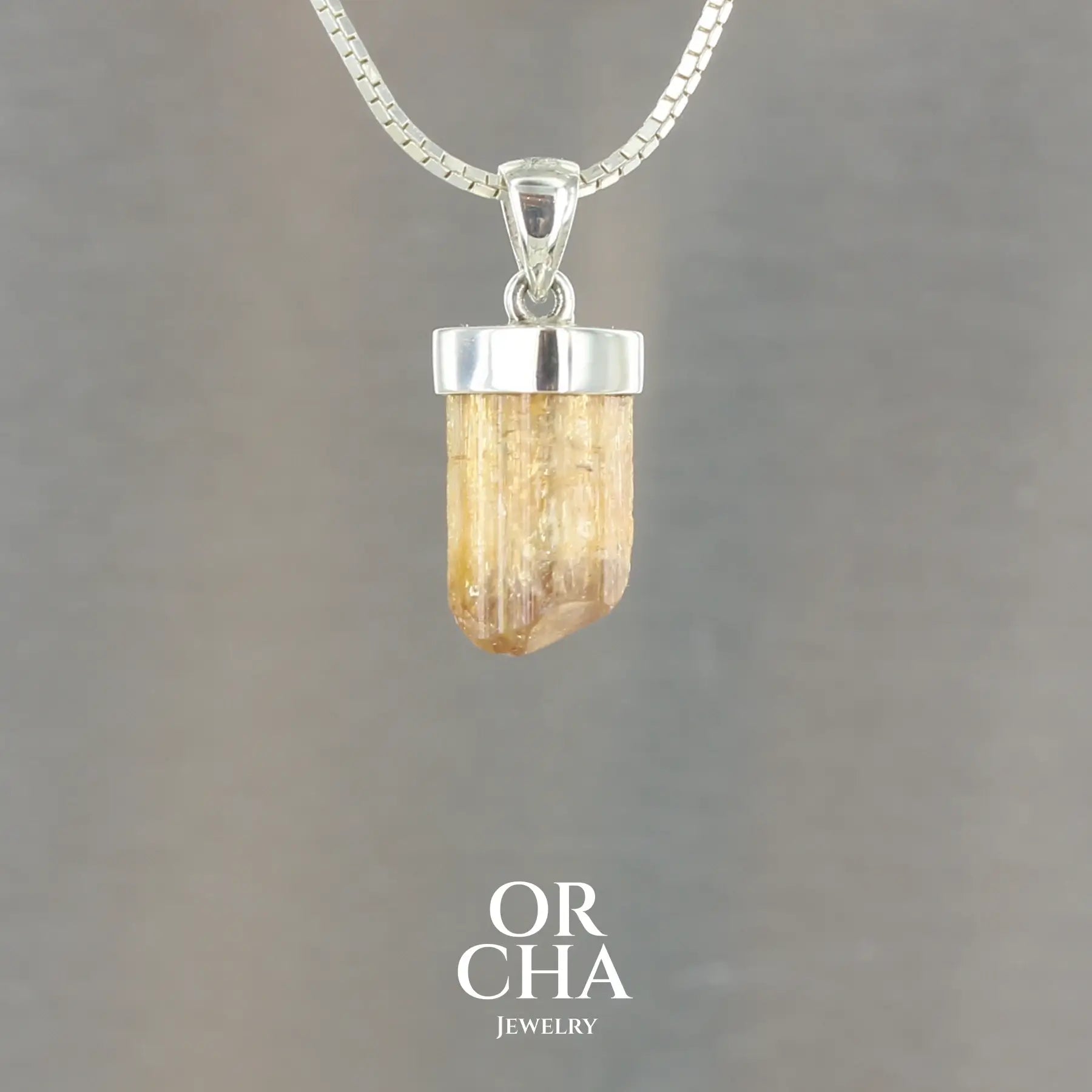 pendentif pour homme en argent massif serti d'un cristal de topaze impériale de couleur jaune doré miel. Pierre brute transparente présentant des inclusions. Bijoux unique, éthique et durable présenté dans un coffret de notre marque, prêt à offrir. Livraison offerte, certificat d'authenticité, service client.
