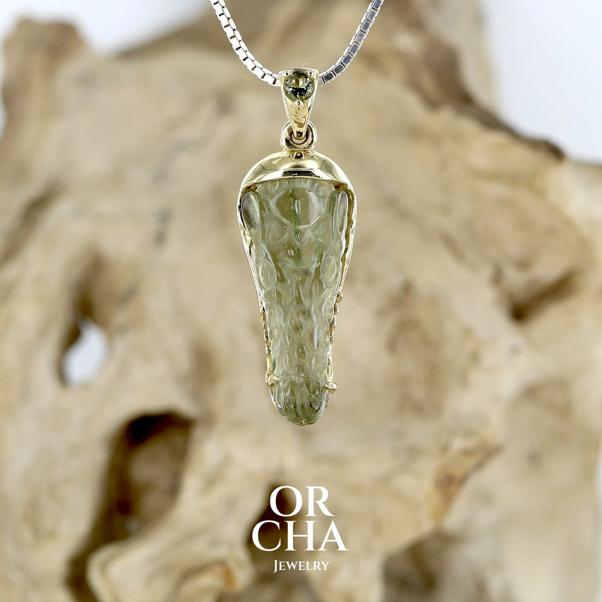 Pendentif pour homme en or 18k serti d'une moldavite sculptée en tête de crocodile. Pierre naturelle de couleur verte kaki translucide. Bijoux unique par Orcha jewelry