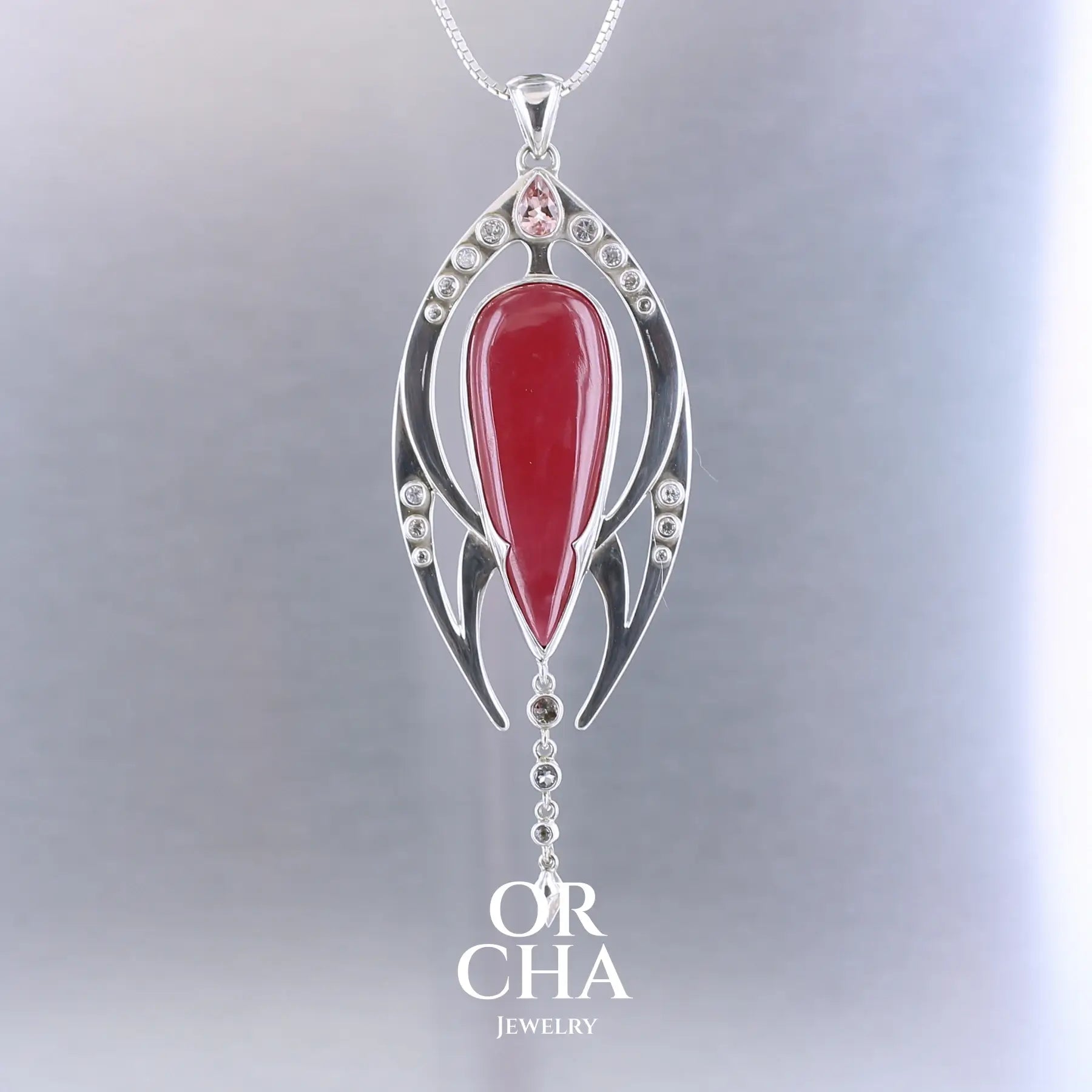 Pendentif exclusif, création originale, pour femme en argent massif serti d'une Rhodonite de très belle qualité, d'une tourmaline et de goshénite. Pierre de couleur rouge coquelicot, rose pastel et blanche, translucide à transparentes. Pierre naturelle, en forme de goutte, taillée en cabochon. Bijoux unique, éthique et durable présenté dans un coffret de notre marque, prêt à offrir. Livraison offerte, certificat d'authenticité, service client