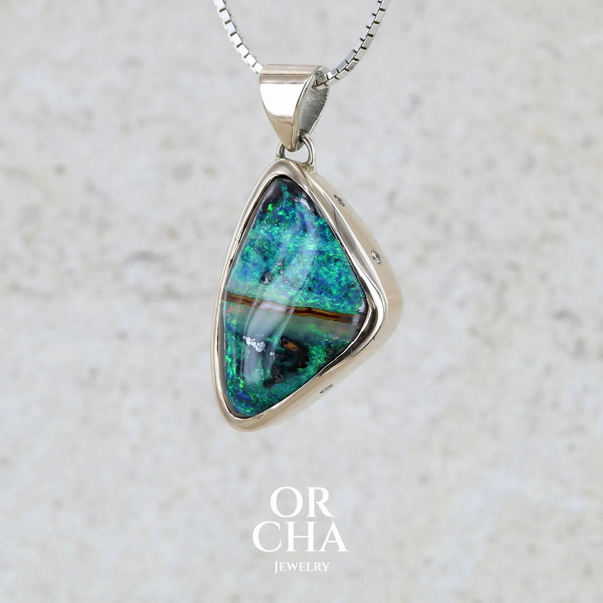 Pendentif pour femme en or 9k massif et argent massif 925 serti d'une opale boulder aux feux multicolores à dominantes bleu turquoise et vert et de six diamants. Pierre cabochon de qualité opaque taillée en forme d'aile. Bijou unique par Orchajewelry