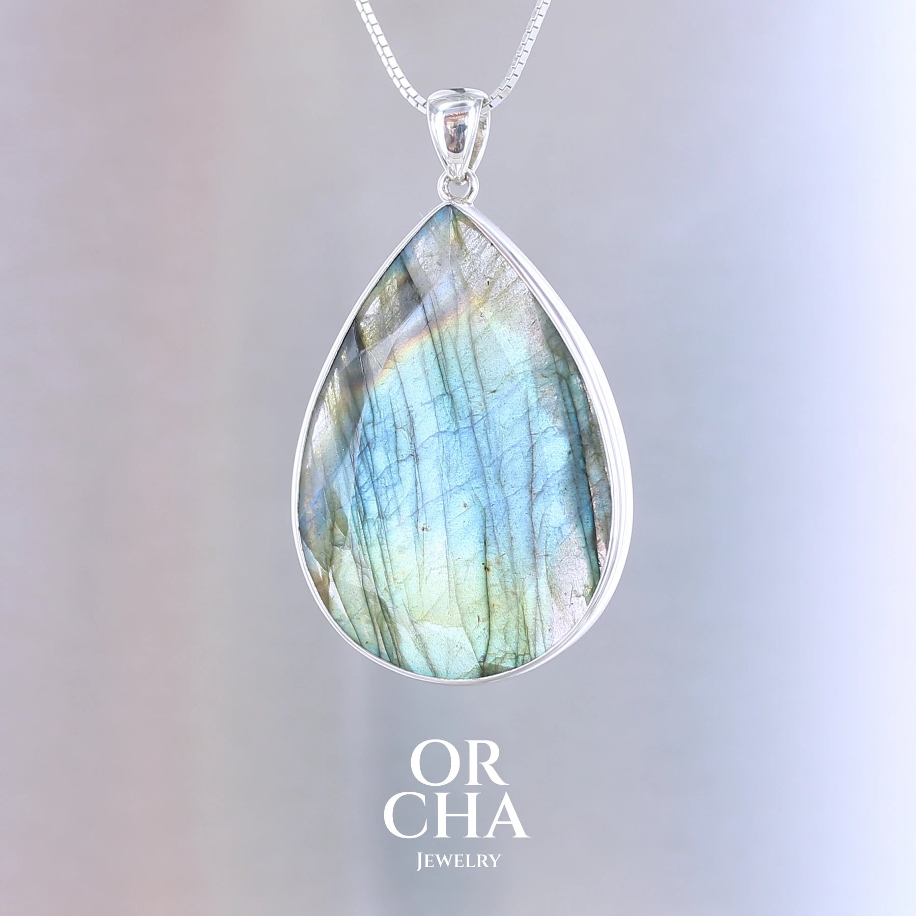 Pendentif pour femme en argent massif sertie d'une labradorite aux reflets bleus, bronzes et multicolores selon la lumière. Pierre facettée naturelle translucide présentant des inclusions fréquents sur ce type de pierre. Bijoux unique, éthique et durable présenté dans un coffret de notre marque, prêt à offrir. Livraison offerte, certificat d'authenticité, service client.
