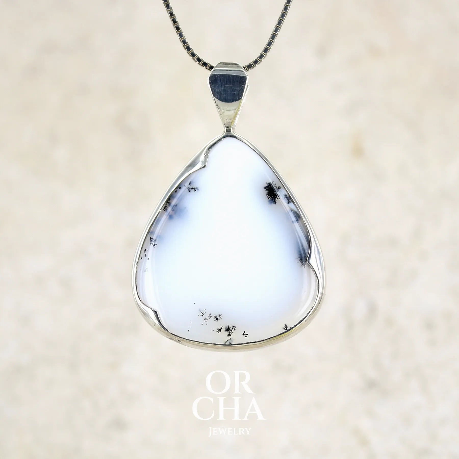 Pendentif pour femme en argent massif sertie d'un cabochon en forme de goutte  d'agate dendritique de couleur blanc pur et noir. Pierre opaque à translucide à inclusions paysages de dendrites de manganèse noires contrastées. Bijou unique réalisé par Orchajewelry