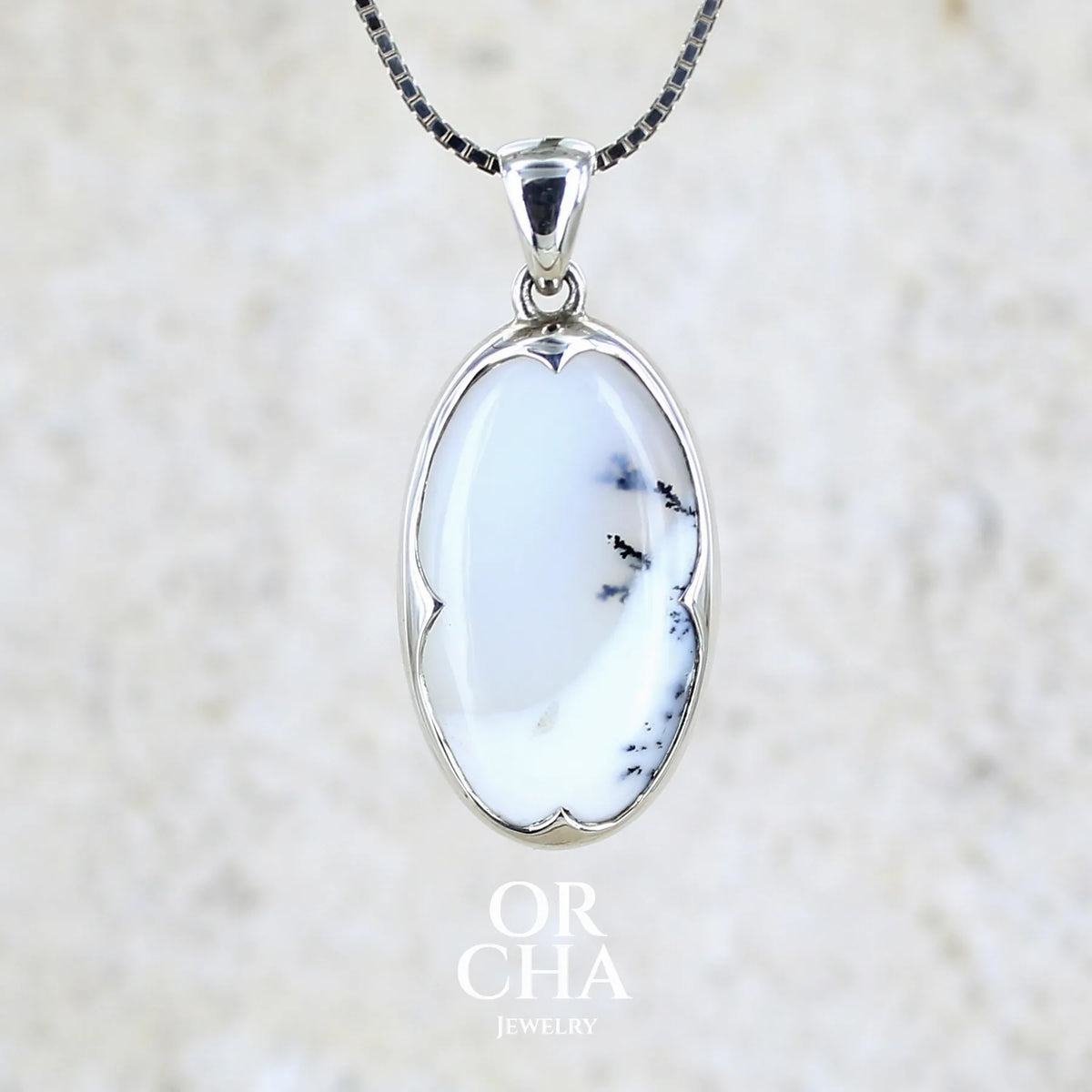 Pendentif pour femme en argent massif sertie d'un cabochon de forme ovale d'agate dendritique de couleur blanc pur et noir. Pierre opaque à translucide à inclusions paysages de dendrites de manganèse noires contrastées. Bijou unique réalisé par Orchajewelry