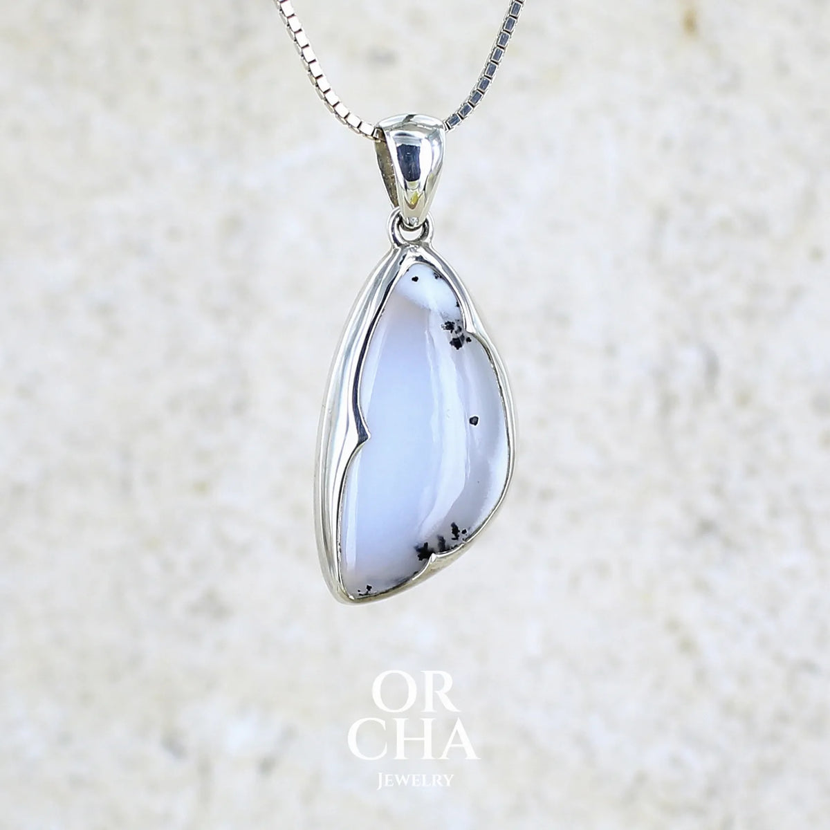 Pendentif pour femme en argent massif sertie d'un cabochon en forme d'aile d'agate dendritique de couleur blanc pur et noir. Pierre opaque à translucide à inclusions paysages de dendrites de manganèse noires contrastées. Bijou unique réalisé par Orchajewelry