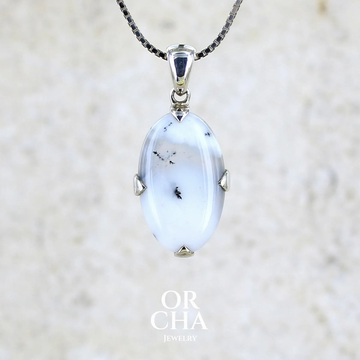Pendentif pour femme en argent massif sertie d'un cabochon de forme ovale d'agate dendritique de couleur blanc pur et noir. Pierre opaque à translucide à inclusions paysages de dendrites de manganèse noires contrastées. Bijou unique réalisé par Orchajewelry