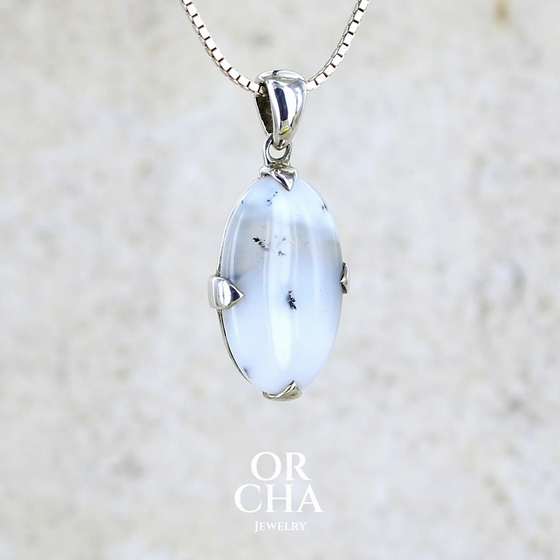 Pendentif pour femme en argent massif sertie d'un cabochon de forme ovale d'agate dendritique de couleur blanc pur et noir. Pierre opaque à translucide à inclusions paysages de dendrites de manganèse noires contrastées. Bijou unique réalisé par Orchajewelry