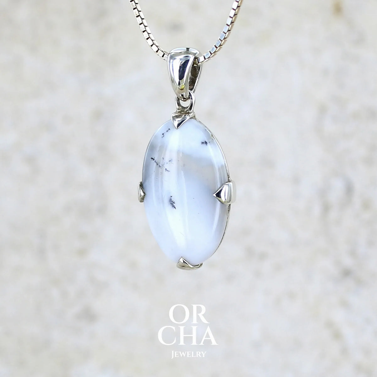 Pendentif pour femme en argent massif sertie d'un cabochon de forme ovale d'agate dendritique de couleur blanc pur et noir. Pierre opaque à translucide à inclusions paysages de dendrites de manganèse noires contrastées. Bijou unique réalisé par Orchajewelry