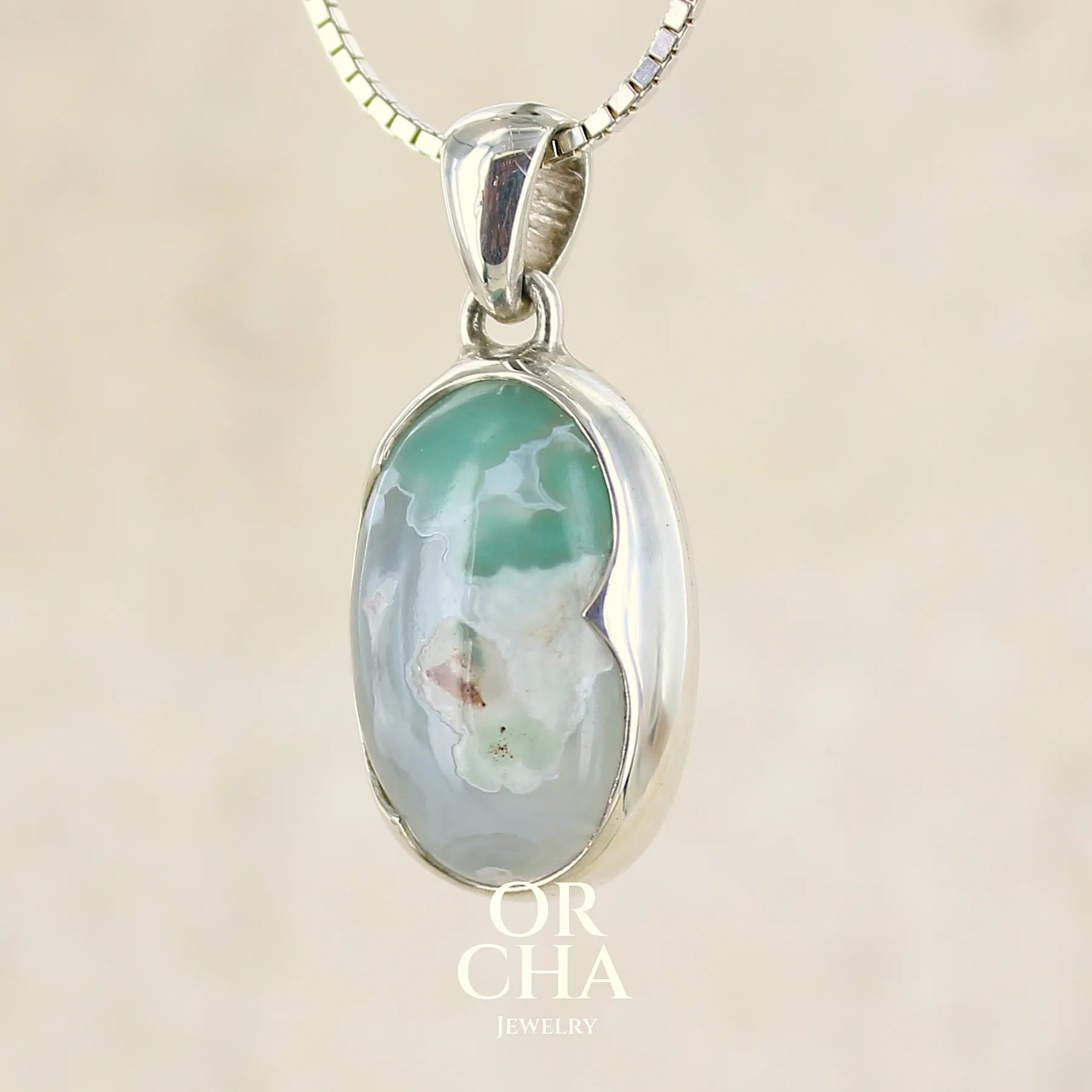 Pendentif ovale en argent massif, serti d'un cabochon de calcédoine de couleur blanche verte. Pierre de qualité translucide comportant des inclusions paysages blanches. Bijoux unique par Orcha Jewelry