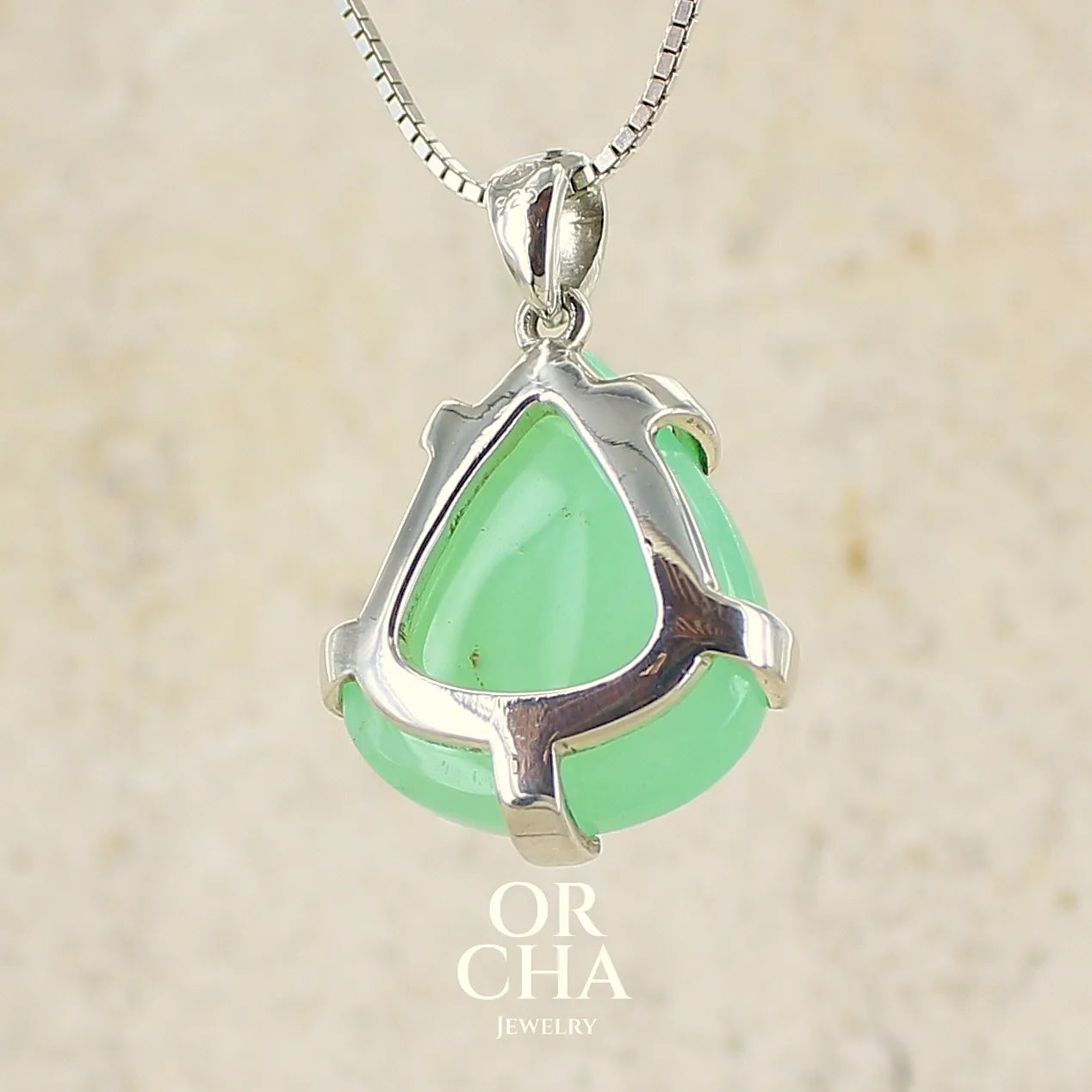 Vue de dos d'un pendentif pour en argent massif, sertie d'un cabochon de chrysoprase de couleur verte claire. Pierre de qualité translucide taillée en cabochon en forme de goutte. Bijoux unique par Orcha jewelry