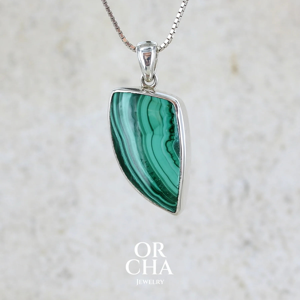 Pendentif pour femme et homme en argent massif serti d'un cabochon de Malachite de couleur verte clair et vert foncé contrasté. Cabochon en forme de dent de qualité opaque. Bijoux unique réalise par Orchajewelry 