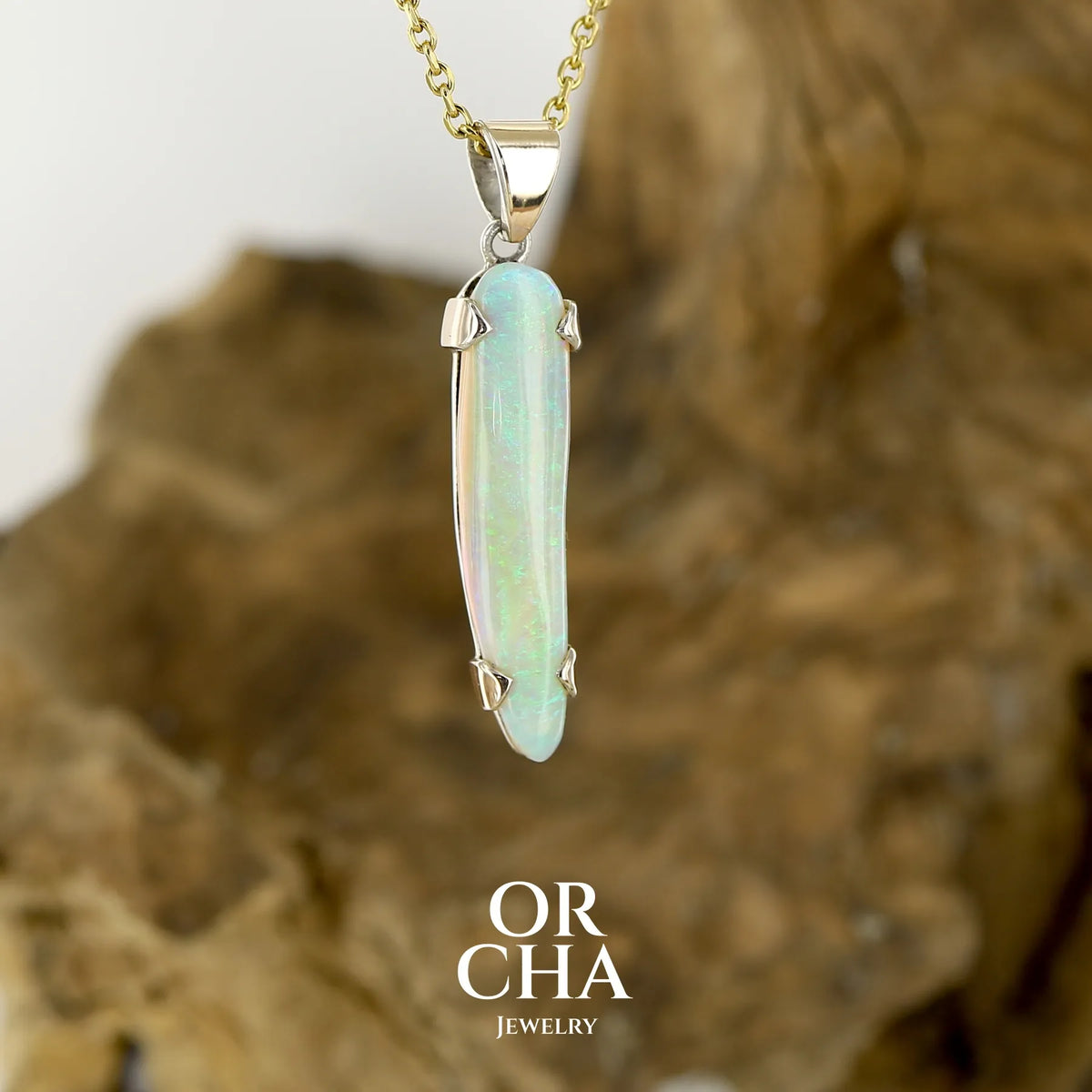 Pendentif pour femme en or jaune massif 18k serti d'une opale cristal aux feux étoilés multicolores à dominantes vert et jaune. Cabochon de 1 carat taille en forme de goutte de qualité transparente. Opale australienne de Mintabie. Bijou unique réalisé par Orchajewelry