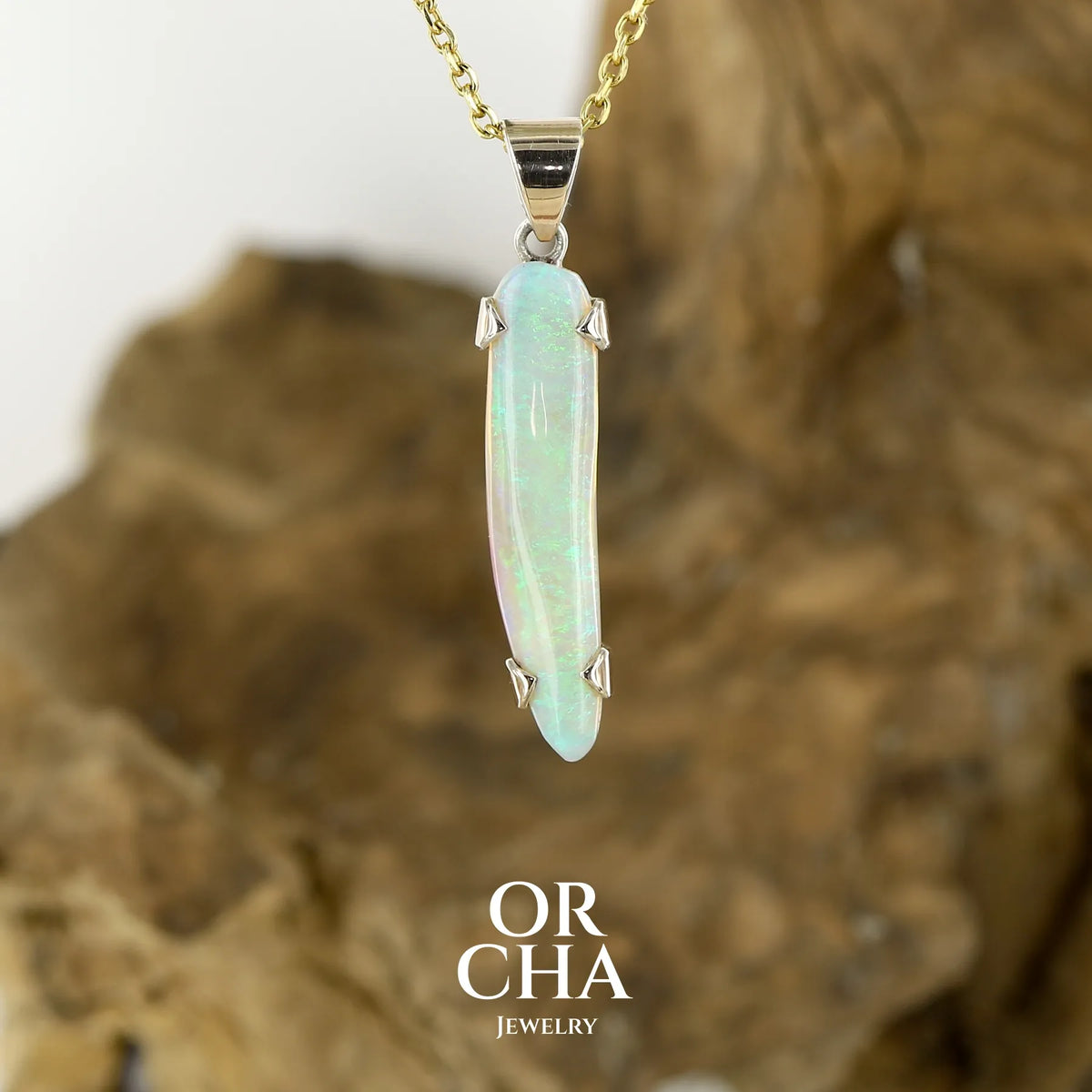 Pendentif pour femme en or jaune massif 18k serti d'une opale cristal aux feux étoilés multicolores à dominantes vert et jaune. Cabochon de 1 carat taille en forme de goutte de qualité transparente. Opale australienne de Mintabie. Bijou unique réalisé par Orchajewelry
