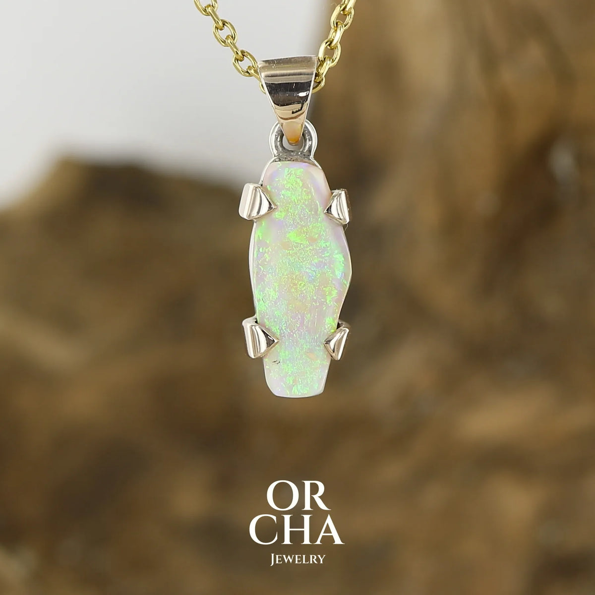 Pendentif pour femme en or 9k et argent massif serti d'une opale cristal aux feux étoilés multicolores à dominantes vert et jaune. Cabochon de 3 carat de forme libre de qualité translucide. Opale australienne. Bijou unique réalisé par Orchajewelry