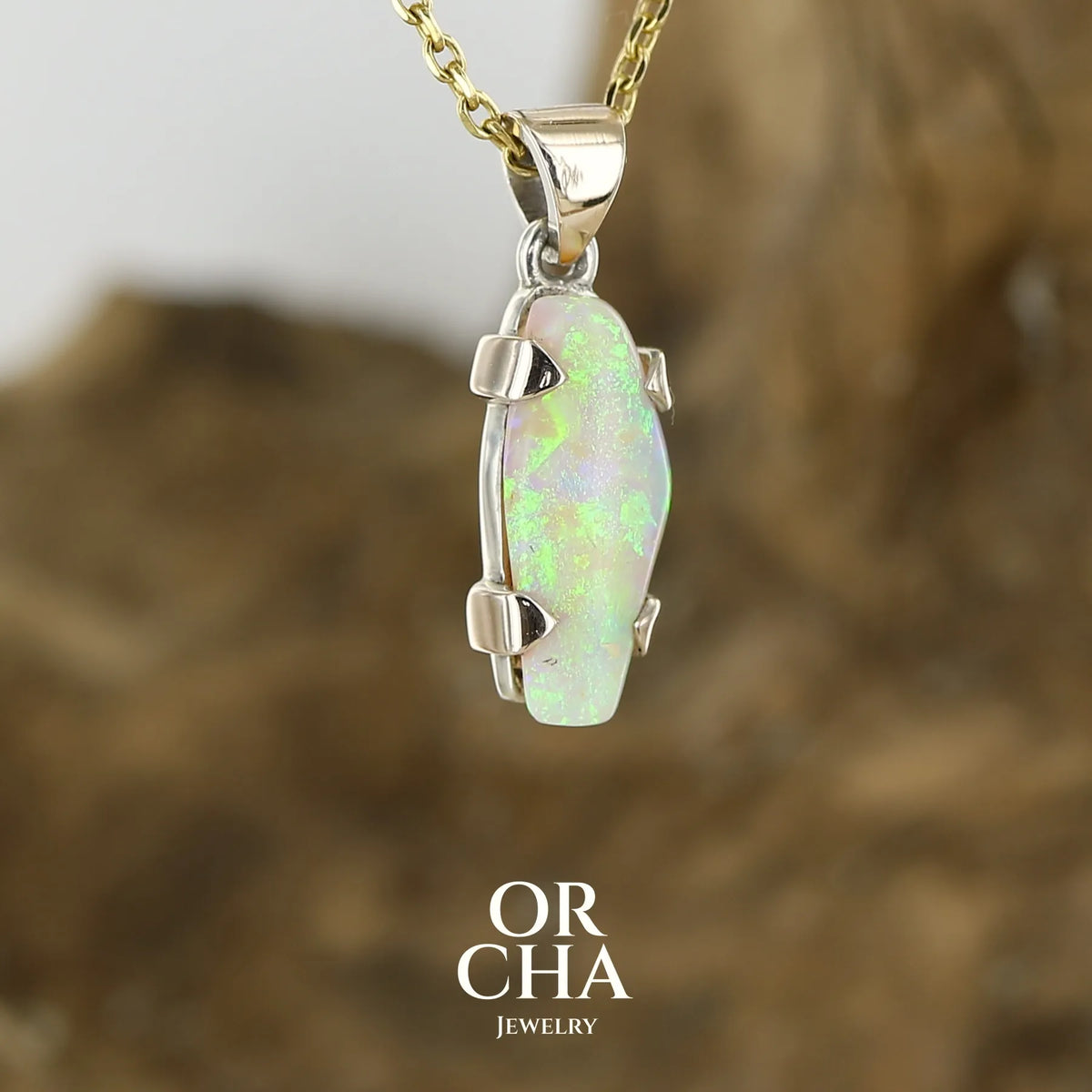 Pendentif pour femme en or 9k et argent massif serti d'une opale cristal aux feux étoilés multicolores à dominantes vert et jaune. Cabochon de 3 carat de forme libre de qualité translucide. Opale australienne. Bijou unique réalisé par Orchajewelry