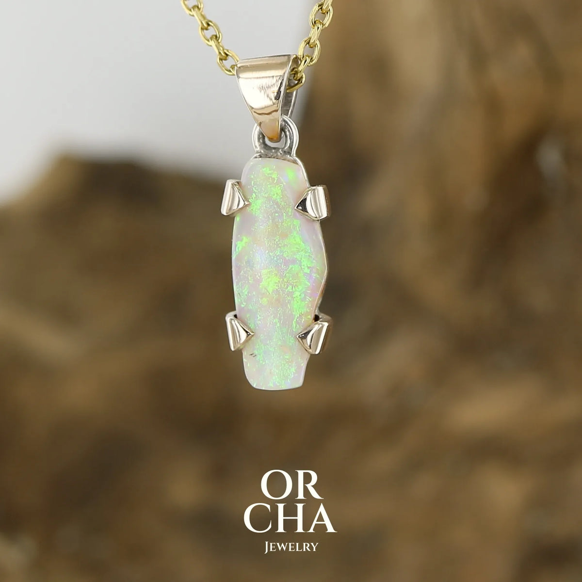 Pendentif pour femme en or 9k et argent massif serti d'une opale cristal aux feux étoilés multicolores à dominantes vert et jaune. Cabochon de 3 carat de forme libre de qualité translucide. Opale australienne. Bijou unique réalisé par Orchajewelry
