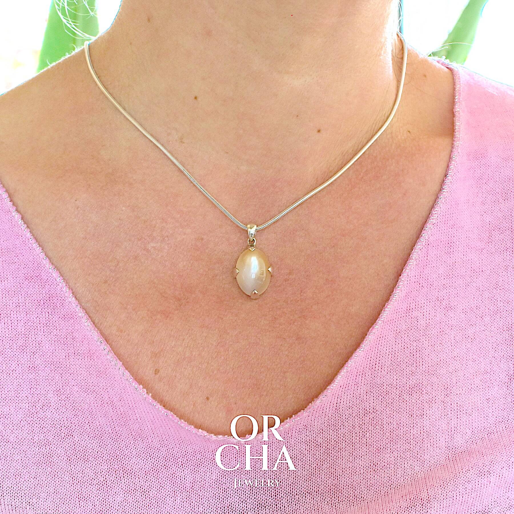 Pendentif pour femme en argent massif serti d'une pierre de lune orange clair, couleur chatoyante à effet satiné. Pierre naturelle cabochon de forme ovale. Bijoux unique, éthique et durable présenté dans un coffret de notre marque, prêt à offrir. Livraison offerte, certificat d'authenticité, service client