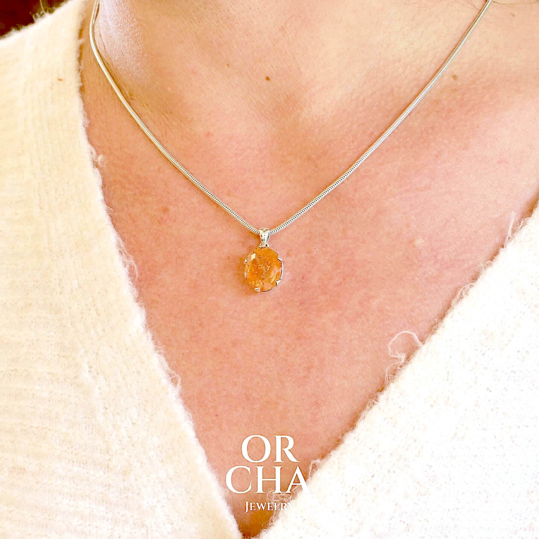 Pendentif en argent massif serti d'une magnifique pierre de soleil. Pierre facettée de forme ovale de qualité transparente. Pierre naturelle de couleur orange clair à scintillement doré et orangé. Bijoux unique, éthique et durable présenté dans un coffret de notre marque, prêt à offrir. Livraison offerte, certificat d'authenticité, service client.