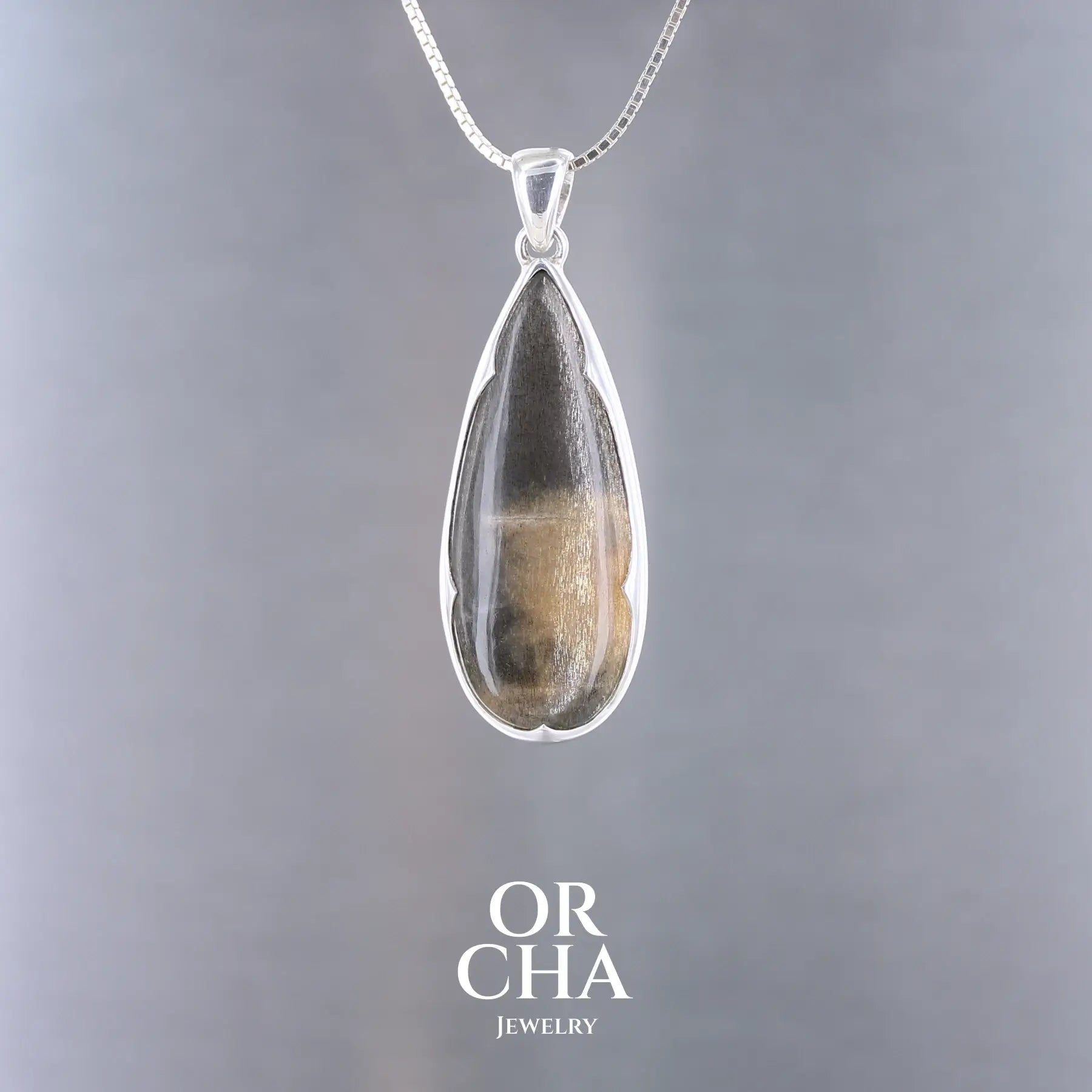 Pendentif en argent massif serti d'une pierre de soleil noire. Pierre naturelle de couleur noire à reflet argentés dorés. Bijoux unique, éthique et durable présenté dans un coffret de notre marque, prêt à offrir. Livraison offerte, certificat d'authenticité, service client.
