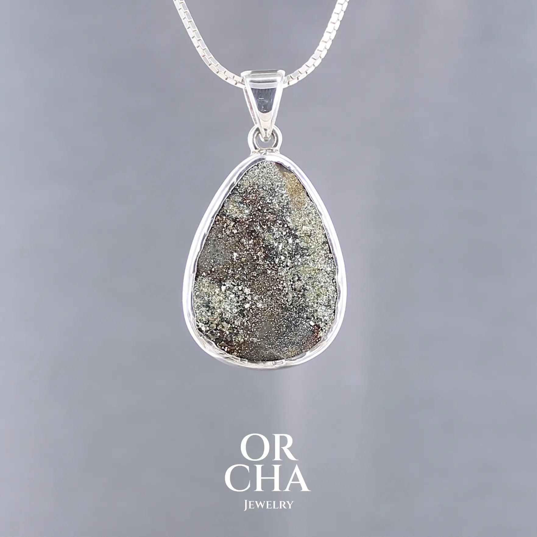 Pendentif en forme de goutte pour femme en argent massif serti d'une pyrite brute scintillante. Pierre naturelle de couleur dorés et brune de qualité Druze scintillante. Bijoux unique, éthique et durable présenté dans un coffret de notre marque, prêt à offrir. Livraison offerte, certificat d'authenticité, service client.