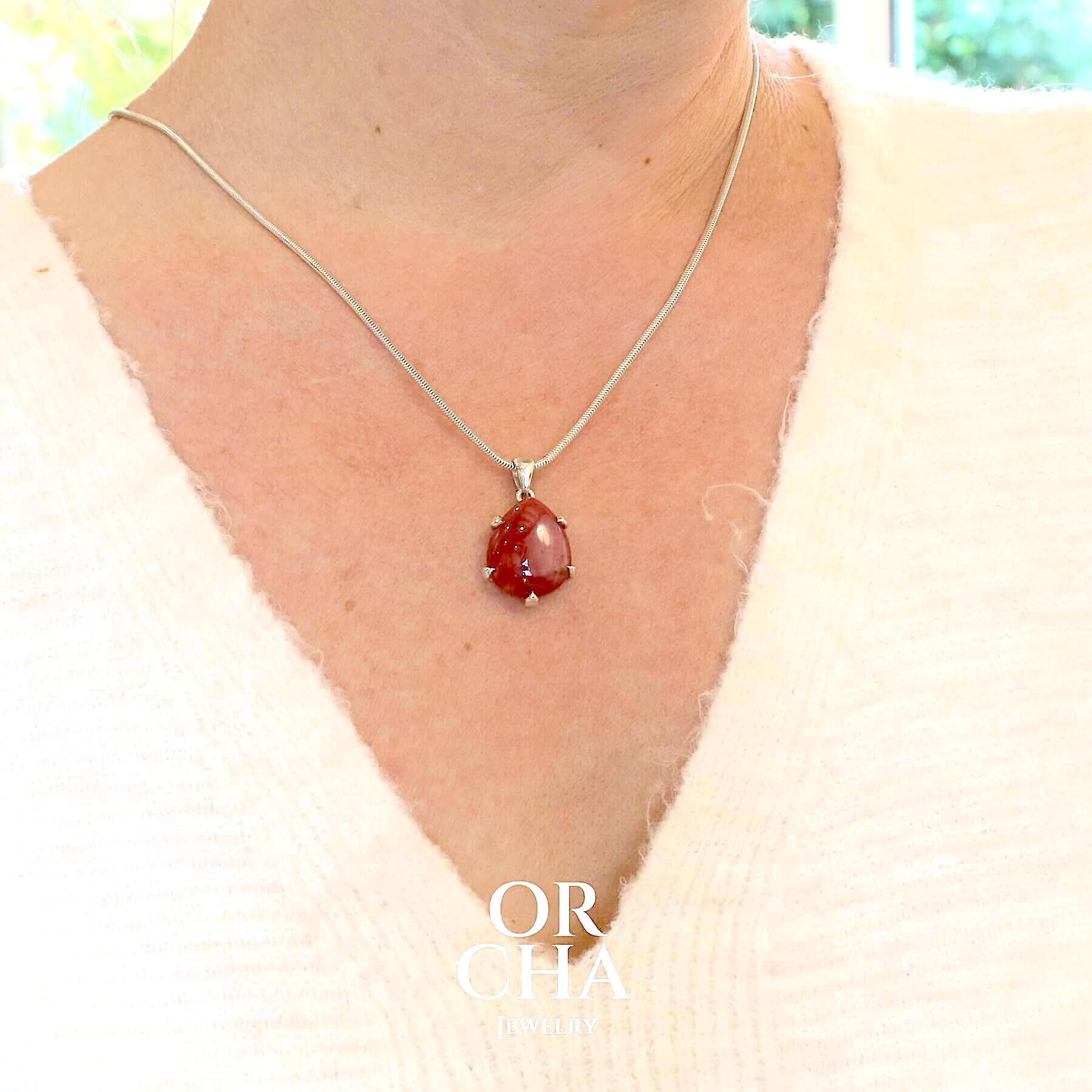 Pendentif pour femme en argent massif  serti d'une Rhodonite de belle qualité. Pierre de couleur rouge coquelicot, opaque à inclusions. Pierre naturelle, en forme de goutte, taillée en cabochon. Bijoux unique, éthique et durable présenté dans un coffret de notre marque, prêt à offrir. Livraison offerte, certificat d'authenticité, service client