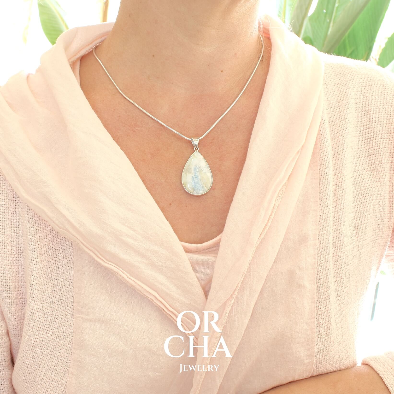 Pendentif pour femme en argent massif sertie d'une scheelite bleue. Pierre naturelle de couleur bleu, beige crème et blanc, de qualité opaque. Bijoux unique, éthique et durable présenté dans un coffret de notre marque, prêt à offrir. Livraison offerte, certificat d'authenticité, service client.