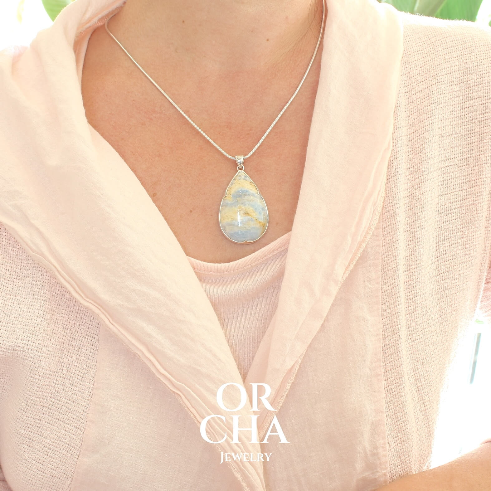 Pendentif pour femme en argent massif serti d'une Scheelite bleue. Pierre naturelle de couleur beige jaune et bleue ,taillée en cabochon en forme de goutte. Bijoux unique, éthique et durable présenté dans un coffret de notre marque, prêt à offrir. Livraison offerte, certificat d'authenticité, service client