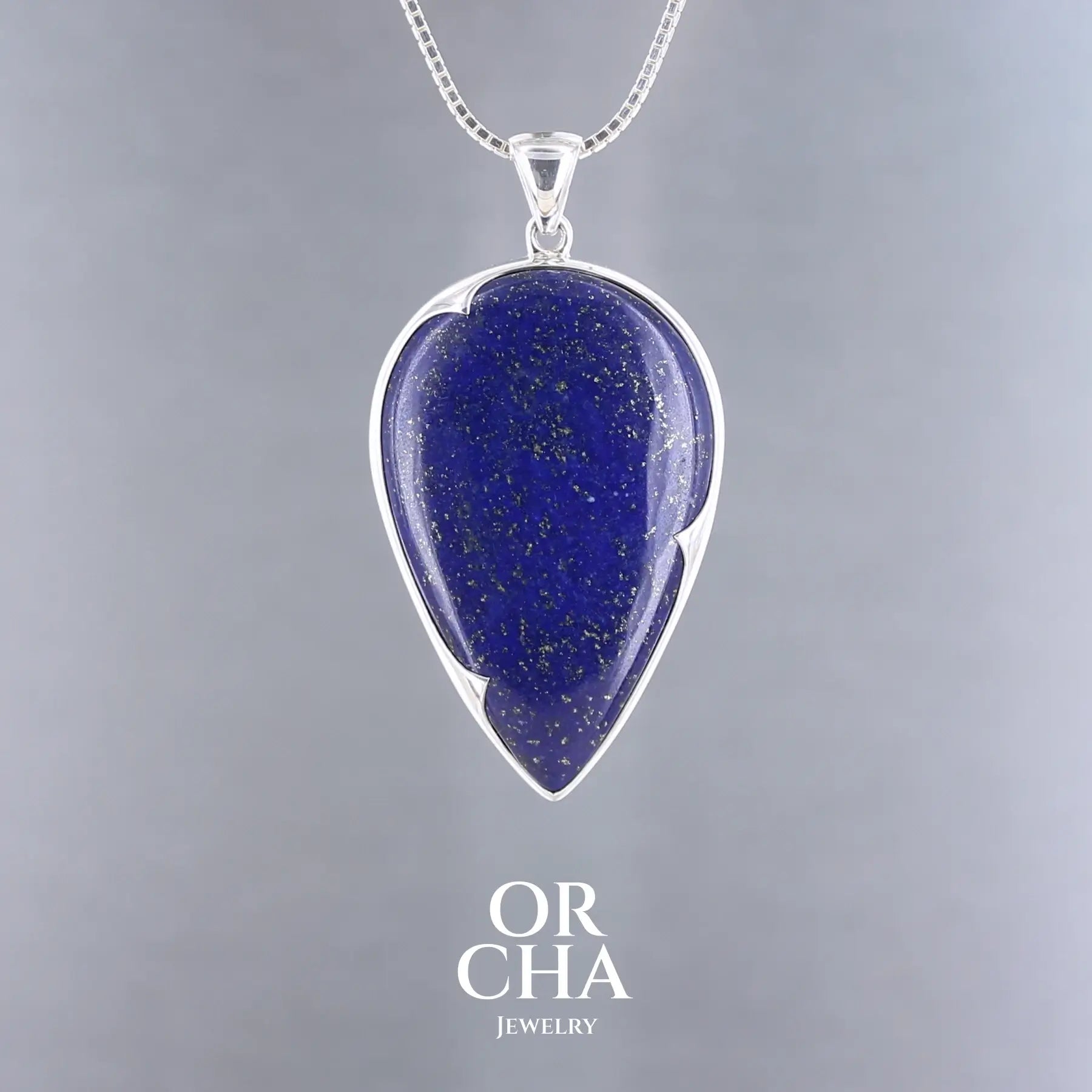 Pendentif artisanal en argent massif 925, serti d’un lapis-lazuli naturel en forme de goutte, souligné par un serti-clos à pointe sur-mesure épousant ses courbes. La pierre bleue intense est constellée de paillettes dorées de pyrite, typiques du lapis-lazuli de qualité. Monté sur une bélière sobre et solide ce pendentif évoque un ciel étoilé. Bijoux unique, éthique et durable présenté dans un coffret de notre marque, prêt à offrir. Livraison offerte, certificat d'authenticité, service client.