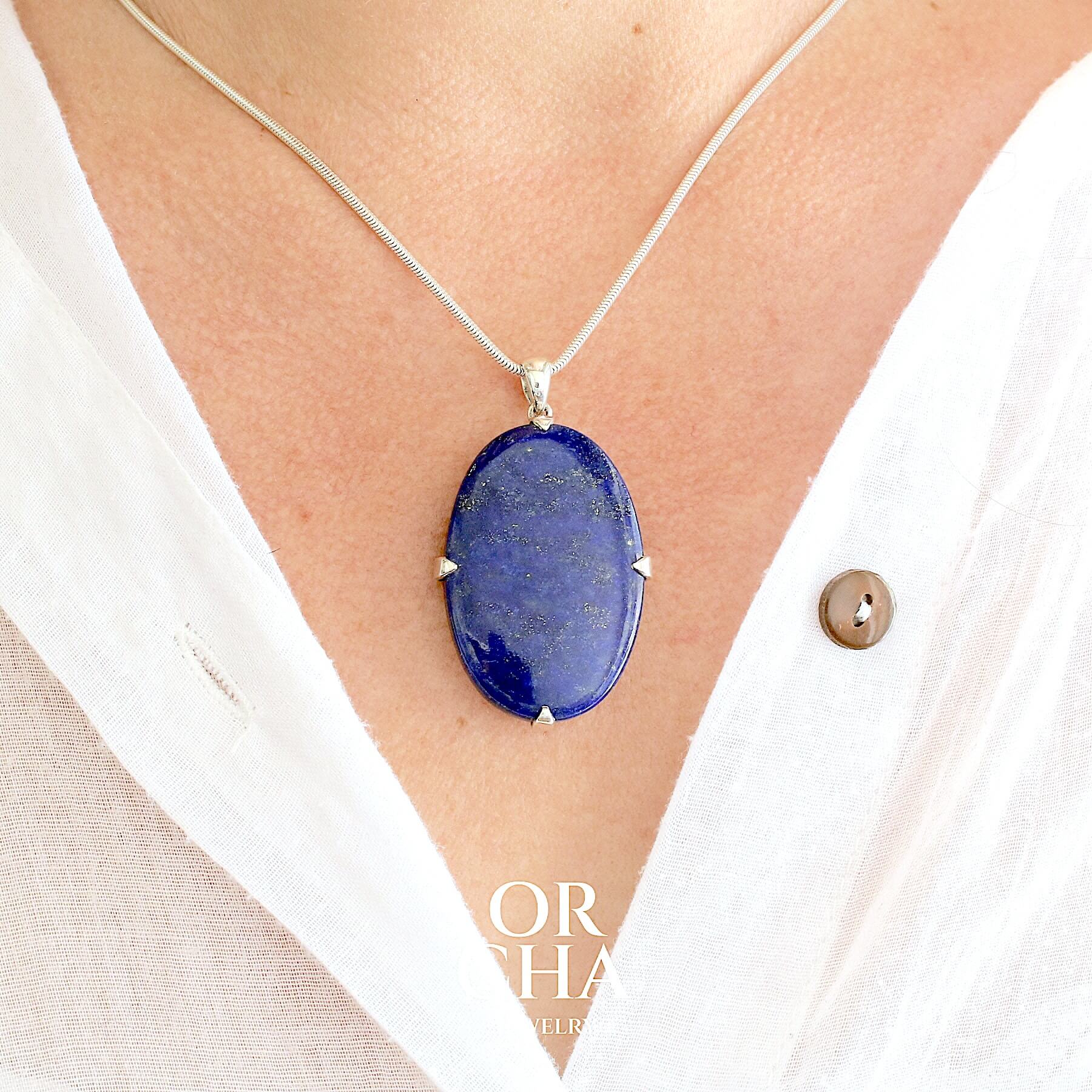 Grand pendentif ovale pour femme en argent massif serti d'un Lapis Lazuli. Pierre naturelle de couleur bleu nuit à inclusions de pyrite dorés, qualité  opaque. Bijoux unique, éthique et durable présenté dans un coffret de notre marque, prêt à offrir. Livraison offerte, certificat d'authenticité, service client.