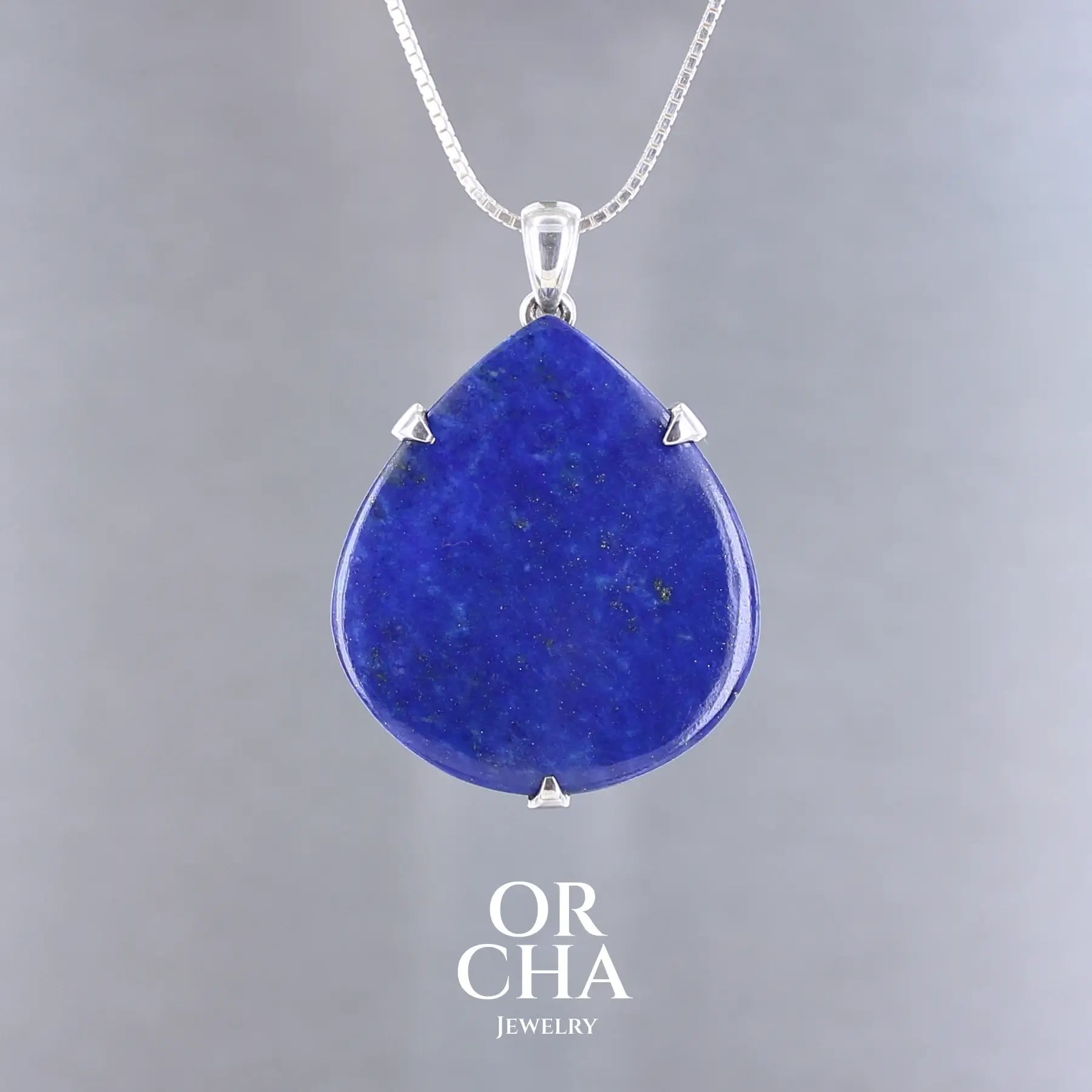 Pendentif goutte en lapis-lazuli bleu profond avec inclusions dorées, serti de trois griffes en argent massif 925. Le bijou, présente une pierre naturelle polie en forme de goutte, montée sur une bélière sobre. Un bijou artisanal unique mettant en valeur la beauté minérale brute et élégante du lapis-lazuli. Bijoux unique, éthique et durable présenté dans un coffret de notre marque, prêt à offrir. Livraison offerte, certificat d'authenticité, service client.

