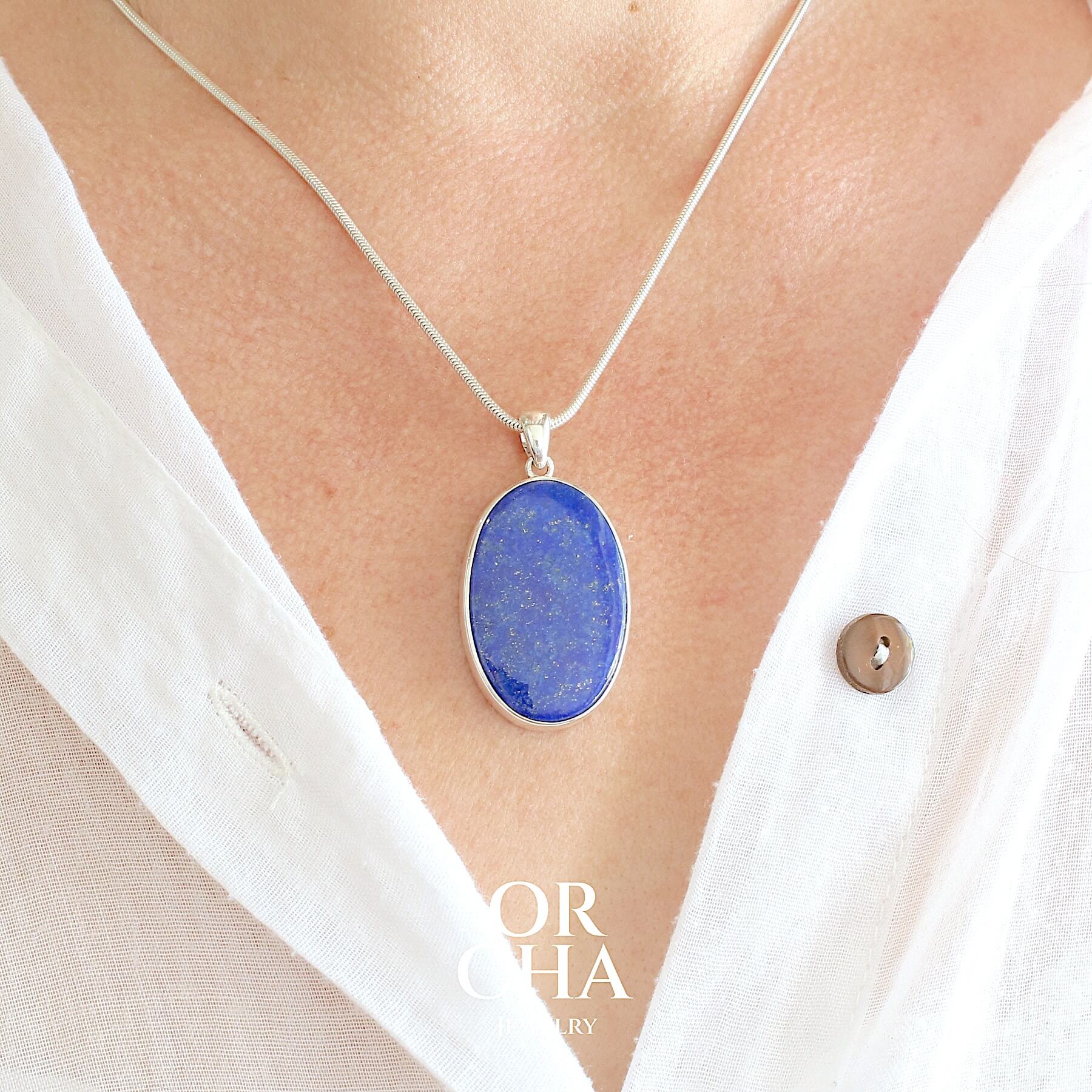 Pendentif ovale pour femme en argent massif serti d'un Lapis Lazuli. Pierre naturelle de couleur bleu nuit à inclusions de pyrite dorés, qualité  opaque. Bijoux unique, éthique et durable présenté dans un coffret de notre marque, prêt à offrir. Livraison offerte, certificat d'authenticité, service client.
