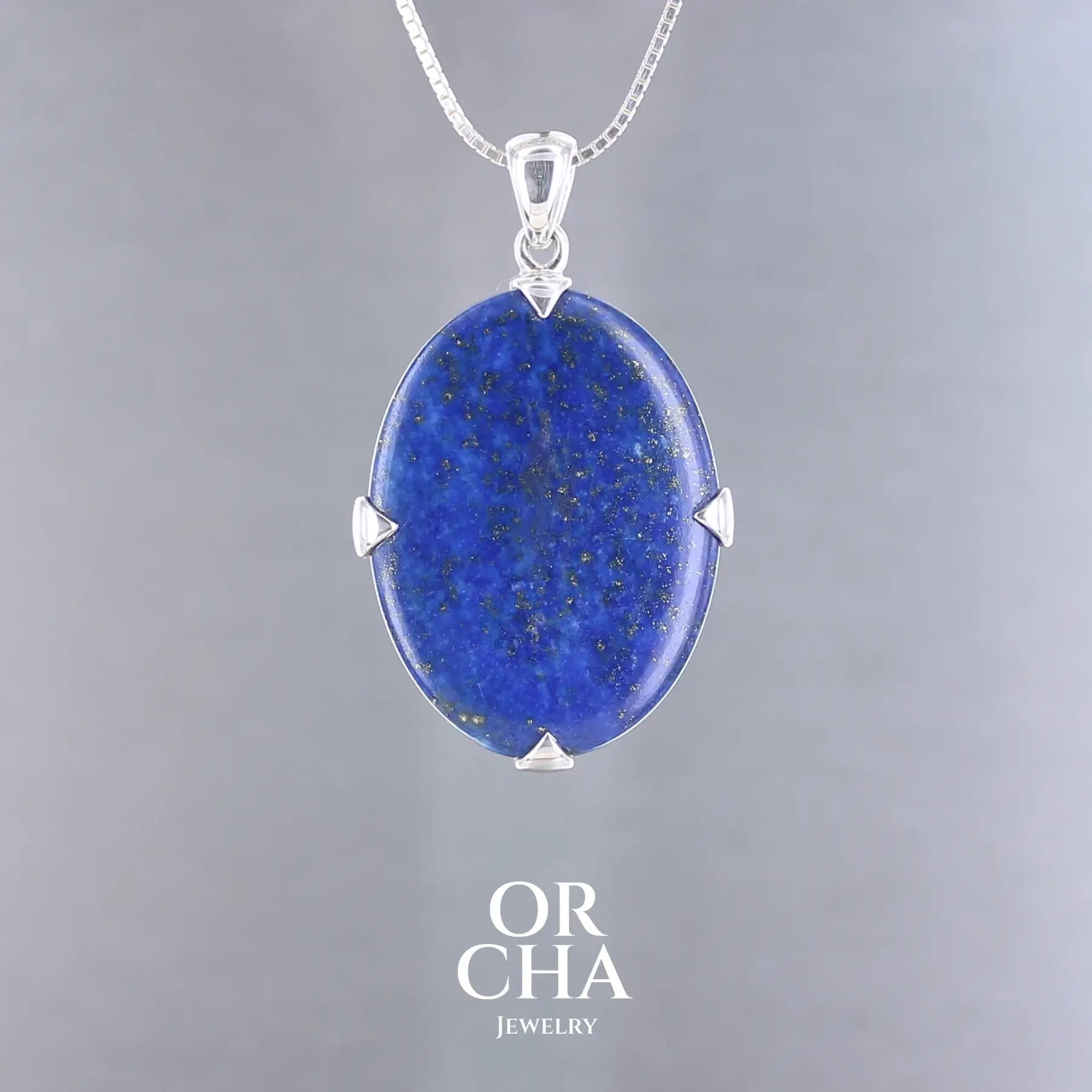Pendentif en lapis-lazuli bleu profond avec inclusions dorées, serti de quatre griffes en argent massif 925. Le bijou, présente une pierre naturelle polie de forme ovale, montée sur une bélière sobre. Un bijou artisanal unique mettant en valeur la beauté minérale brute et élégante du lapis-lazuli. Bijoux unique, éthique et durable présenté dans un coffret de notre marque, prêt à offrir. Livraison offerte, certificat d'authenticité, service client.
