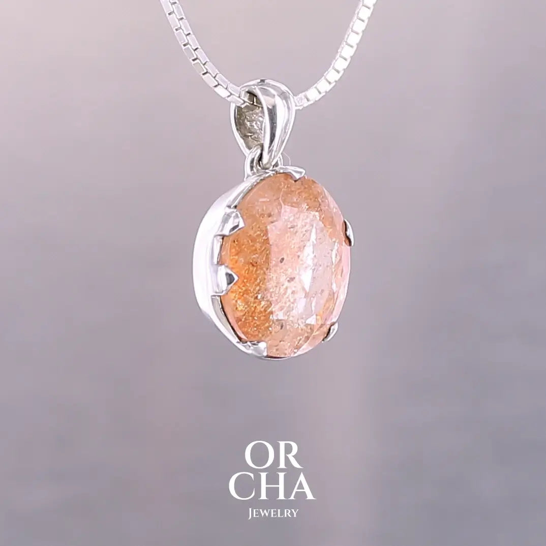 Pendentif en argent massif serti d'une magnifique pierre de soleil. Pierre facettée de forme ovale de qualité transparente. Pierre naturelle de couleur orange clair à scintillement doré et orangé. Bijoux unique, éthique et durable présenté dans un coffret de notre marque, prêt à offrir. Livraison offerte, certificat d'authenticité, service client.