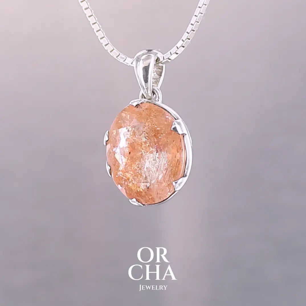 Pendentif en argent massif serti d'une magnifique pierre de soleil. Pierre facettée de forme ovale de qualité transparente. Pierre naturelle de couleur orange clair à scintillement doré et orangé. Bijoux unique, éthique et durable présenté dans un coffret de notre marque, prêt à offrir. Livraison offerte, certificat d'authenticité, service client.