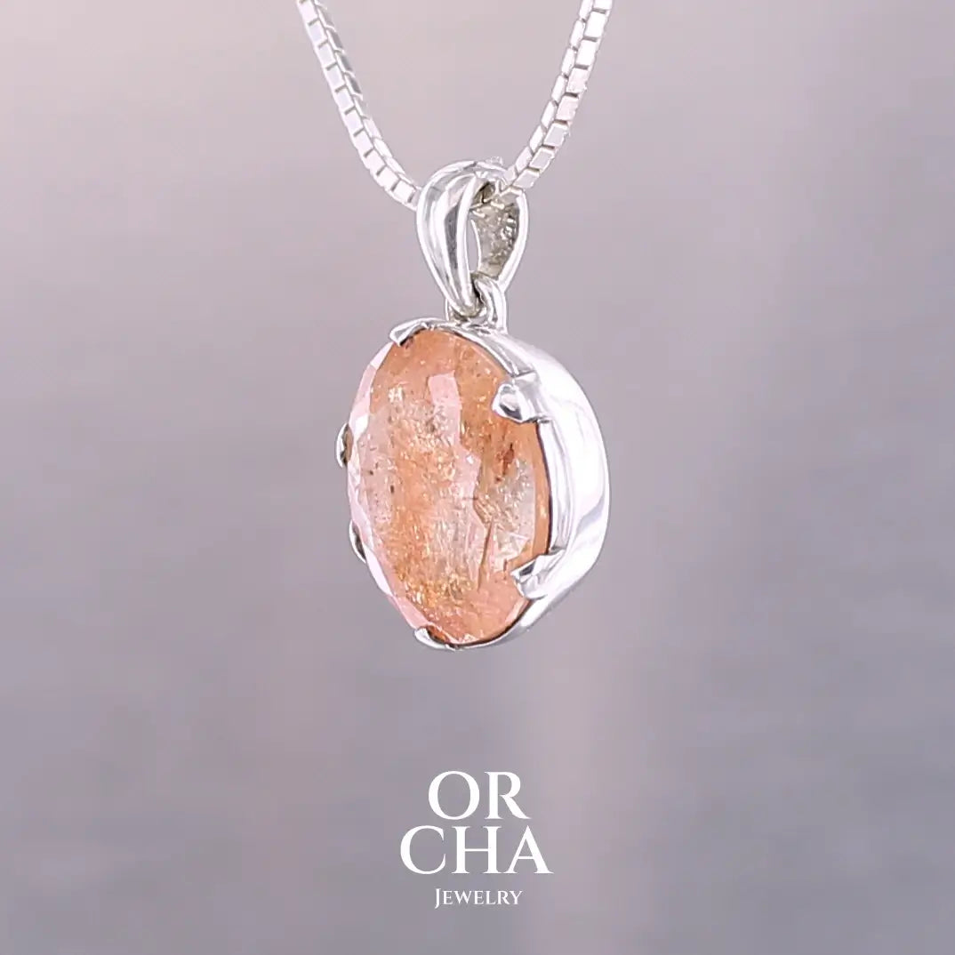 Pendentif en argent massif serti d'une magnifique pierre de soleil. Pierre facettée de forme ovale de qualité transparente. Pierre naturelle de couleur orange clair à scintillement doré et orangé. Bijoux unique, éthique et durable présenté dans un coffret de notre marque, prêt à offrir. Livraison offerte, certificat d'authenticité, service client.