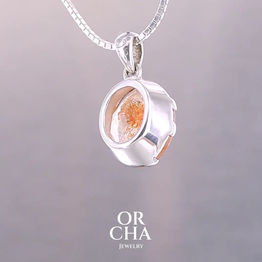 Pendentif en argent massif serti d'une magnifique pierre de soleil. Pierre facettée de forme ovale de qualité transparente. Pierre naturelle de couleur orange clair à scintillement doré et orangé. Bijoux unique, éthique et durable présenté dans un coffret de notre marque, prêt à offrir. Livraison offerte, certificat d'authenticité, service client.