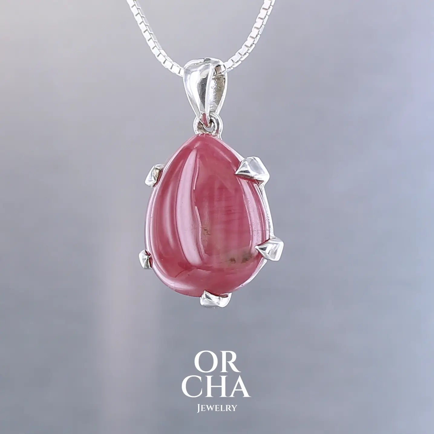 Pendentif pour femme en argent massif  serti d'une Rhodonite de belle qualité. Pierre de couleur rouge coquelicot, opaque à inclusions. Pierre naturelle, en forme de goutte, taillée en cabochon. Bijoux unique, éthique et durable présenté dans un coffret de notre marque, prêt à offrir. Livraison offerte, certificat d'authenticité, service client