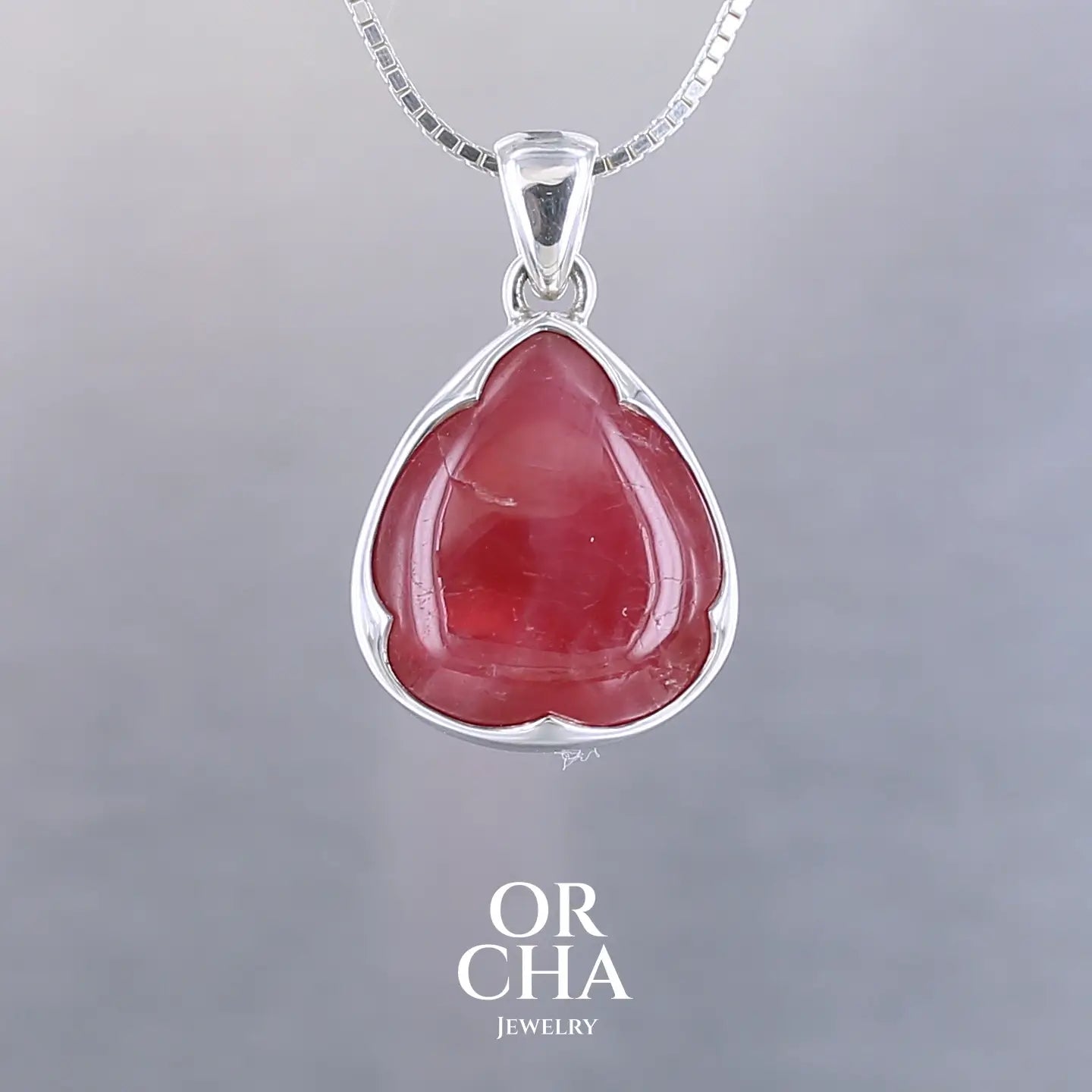 Pendentif pour femme en argent massif  serti d'une Rhodonite de belle qualité. Pierre de couleur rouge coquelicot, opaque à inclusions. Pierre naturelle, en forme de goutte, taillée en cabochon. Bijoux unique, éthique et durable présenté dans un coffret de notre marque, prêt à offrir. Livraison offerte, certificat d'authenticité, service client
