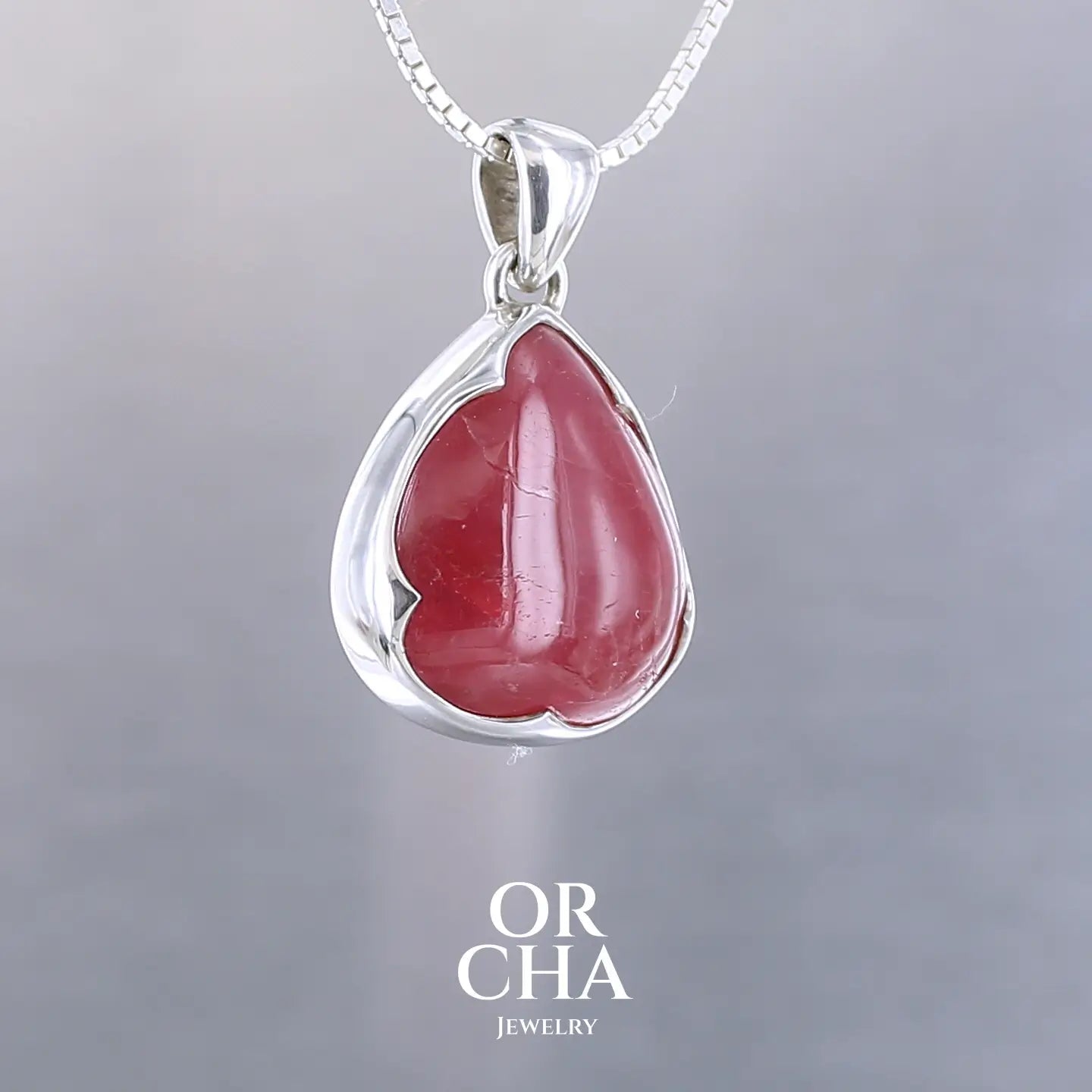 Pendentif pour femme en argent massif  serti d'une Rhodonite de belle qualité. Pierre de couleur rouge coquelicot, opaque à inclusions. Pierre naturelle, en forme de goutte, taillée en cabochon. Bijoux unique, éthique et durable présenté dans un coffret de notre marque, prêt à offrir. Livraison offerte, certificat d'authenticité, service client
