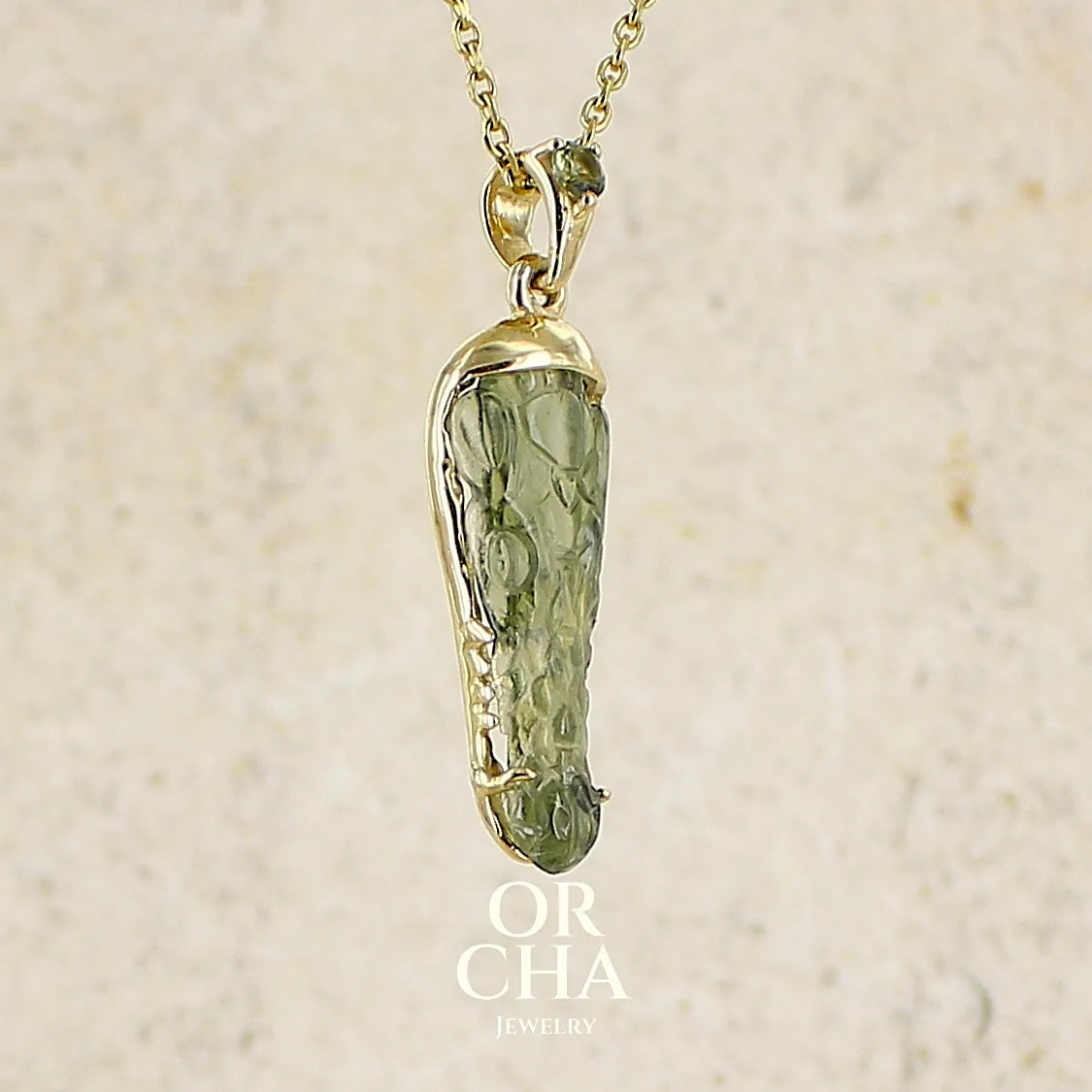 Pendentif pour homme en or 18k serti d'une moldavite sculptée en tête de crocodile. Pierre naturelle de couleur verte kaki translucide. Bijoux unique par Orcha jewelry