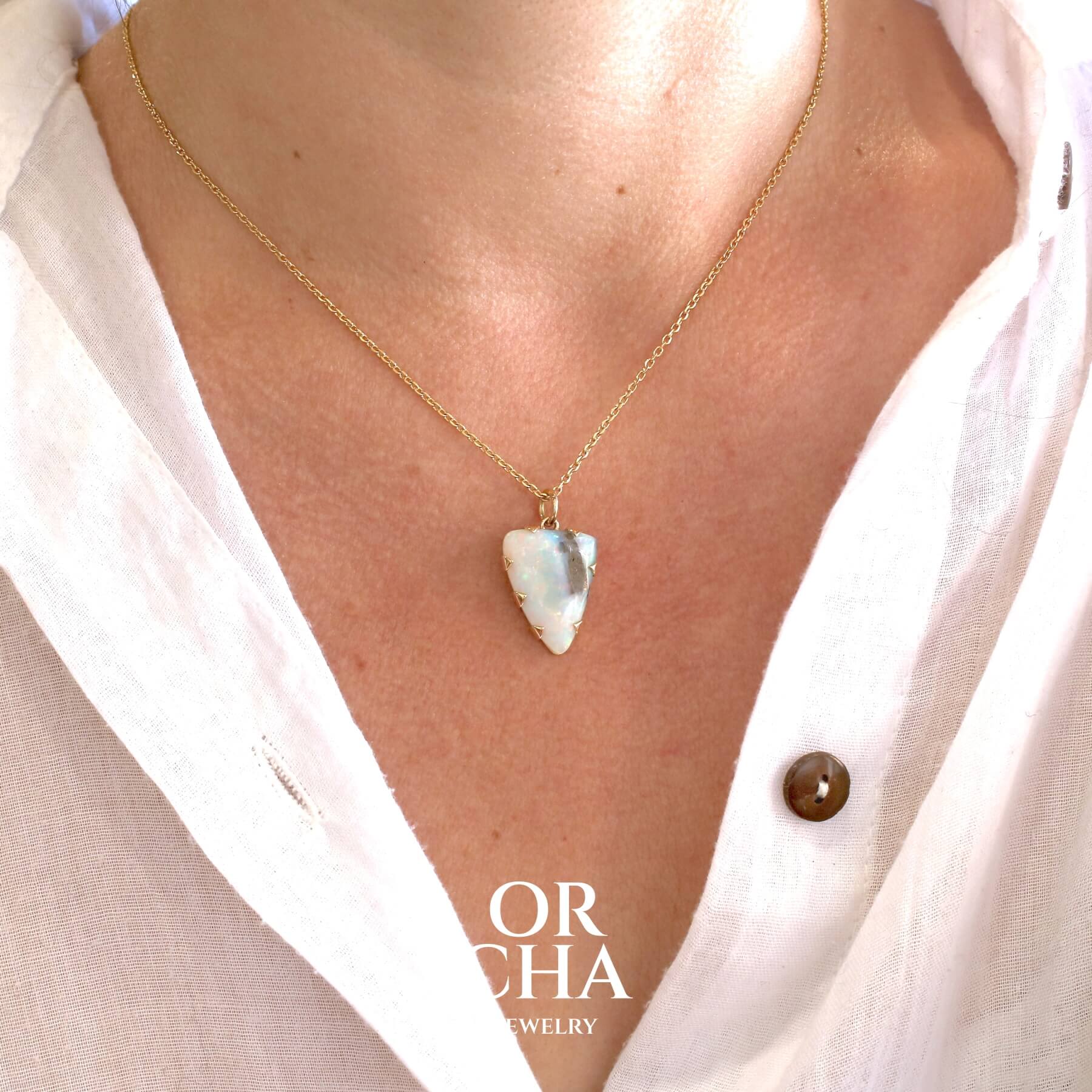 Pendentif pour femme en or jaune massif  18k serti d'une opale boulder aux feux multicolores. Majoritairement blanche une inclusion de matrice brune ressort en surface de la pierre, lui conférant un charme fou. Pierre naturelle taillée en cabochon de forme libre serti de griffe. Bijoux unique, éthique et durable présenté dans un coffret de notre marque, prêt à offrir. Livraison offerte, certificat d'authenticité, service client
