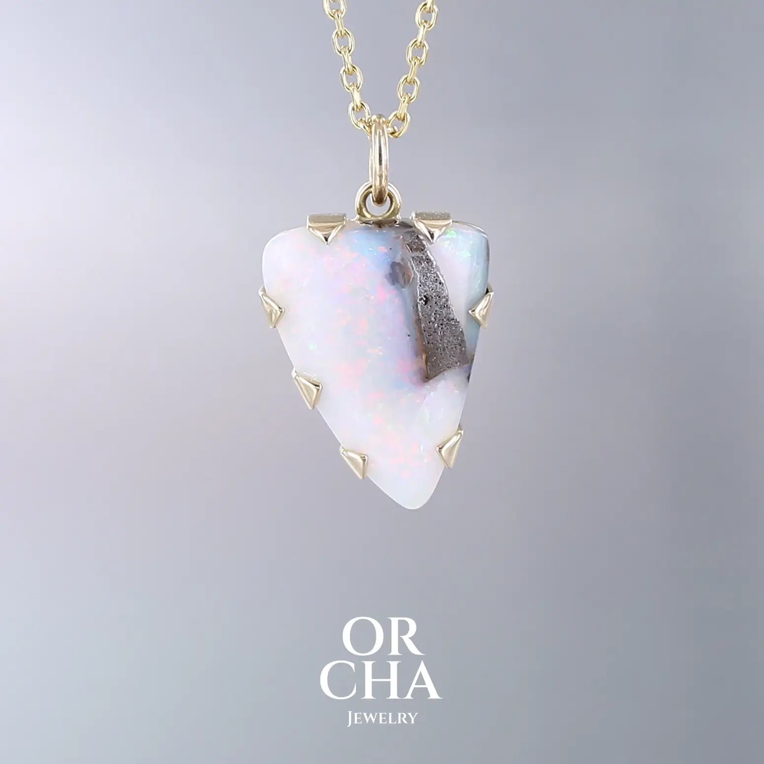 Pendentif pour femme en or jaune massif  18k serti d'une opale boulder aux feux multicolores. Majoritairement blanche une inclusion de matrice brune ressort en surface de la pierre, lui conférant un charme fou. Pierre naturelle taillée en cabochon de forme libre serti de griffe. Bijoux unique, éthique et durable présenté dans un coffret de notre marque, prêt à offrir. Livraison offerte, certificat d'authenticité, service client
